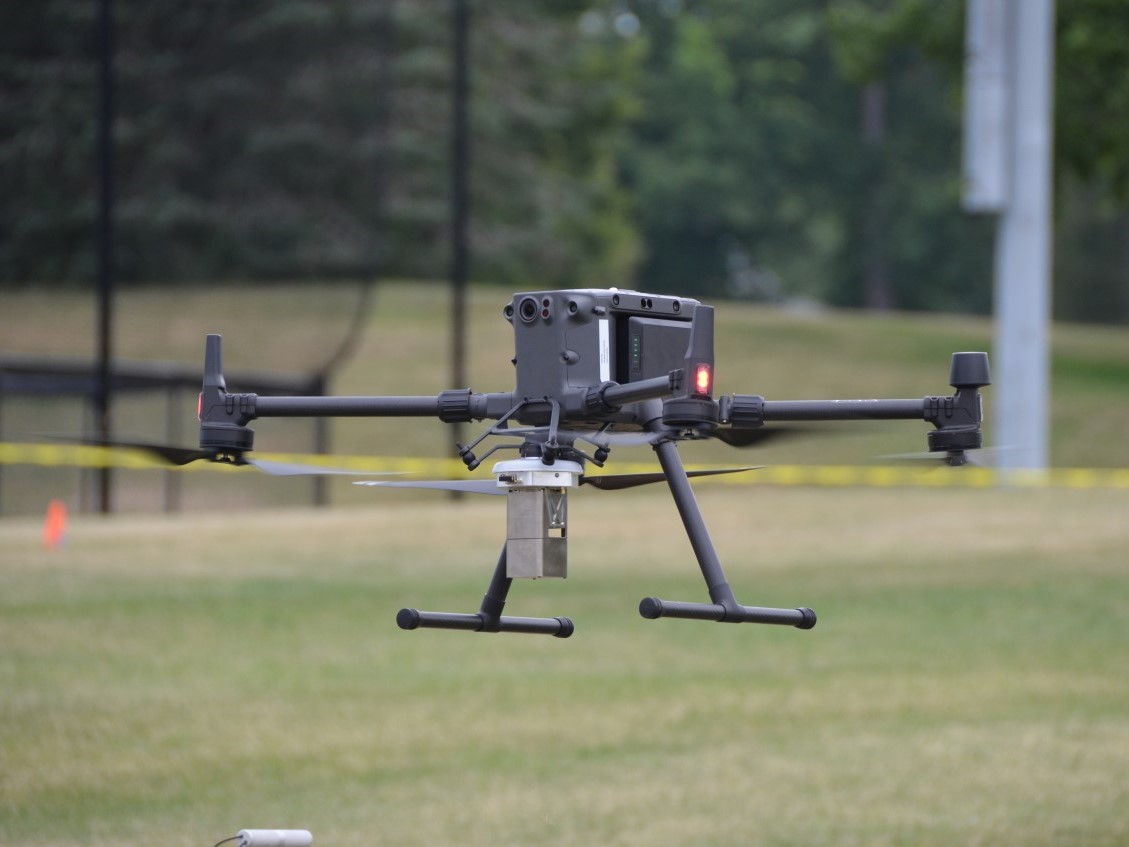 Black drone hovering over a field