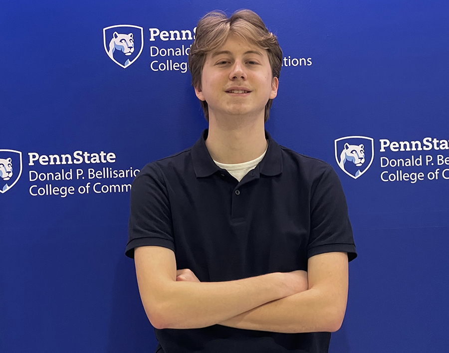 A student smiling with arms crossed