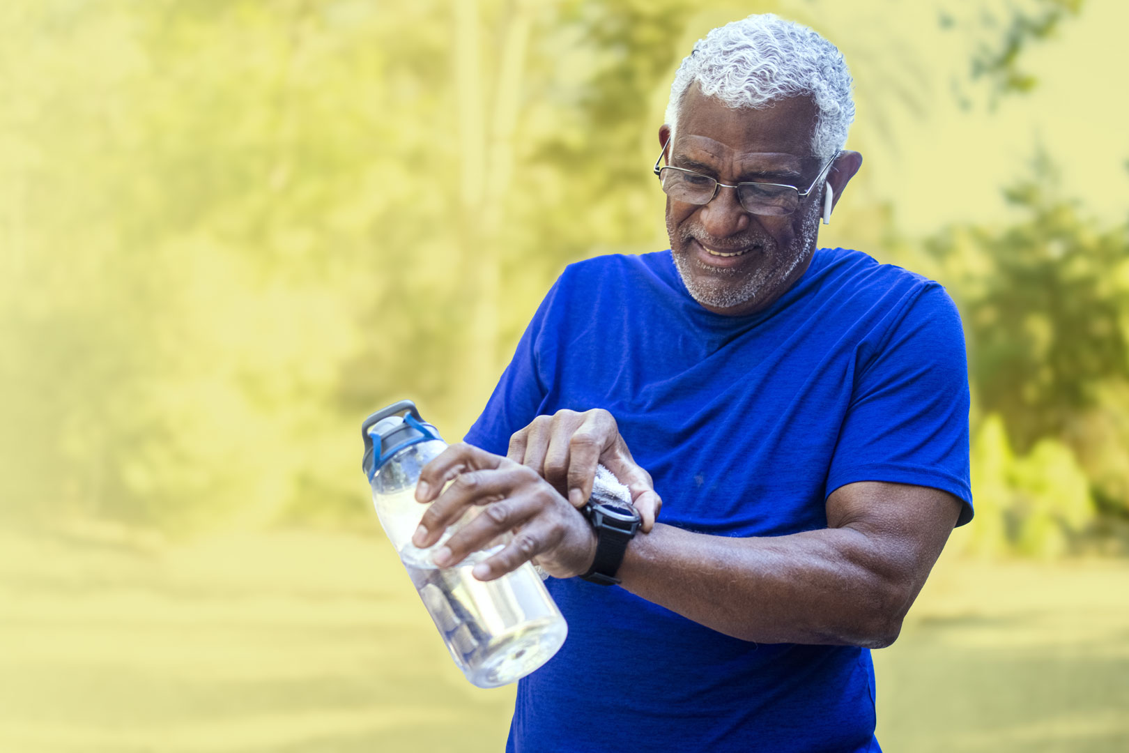 Older man holding a water bottle and checking his smartwatch