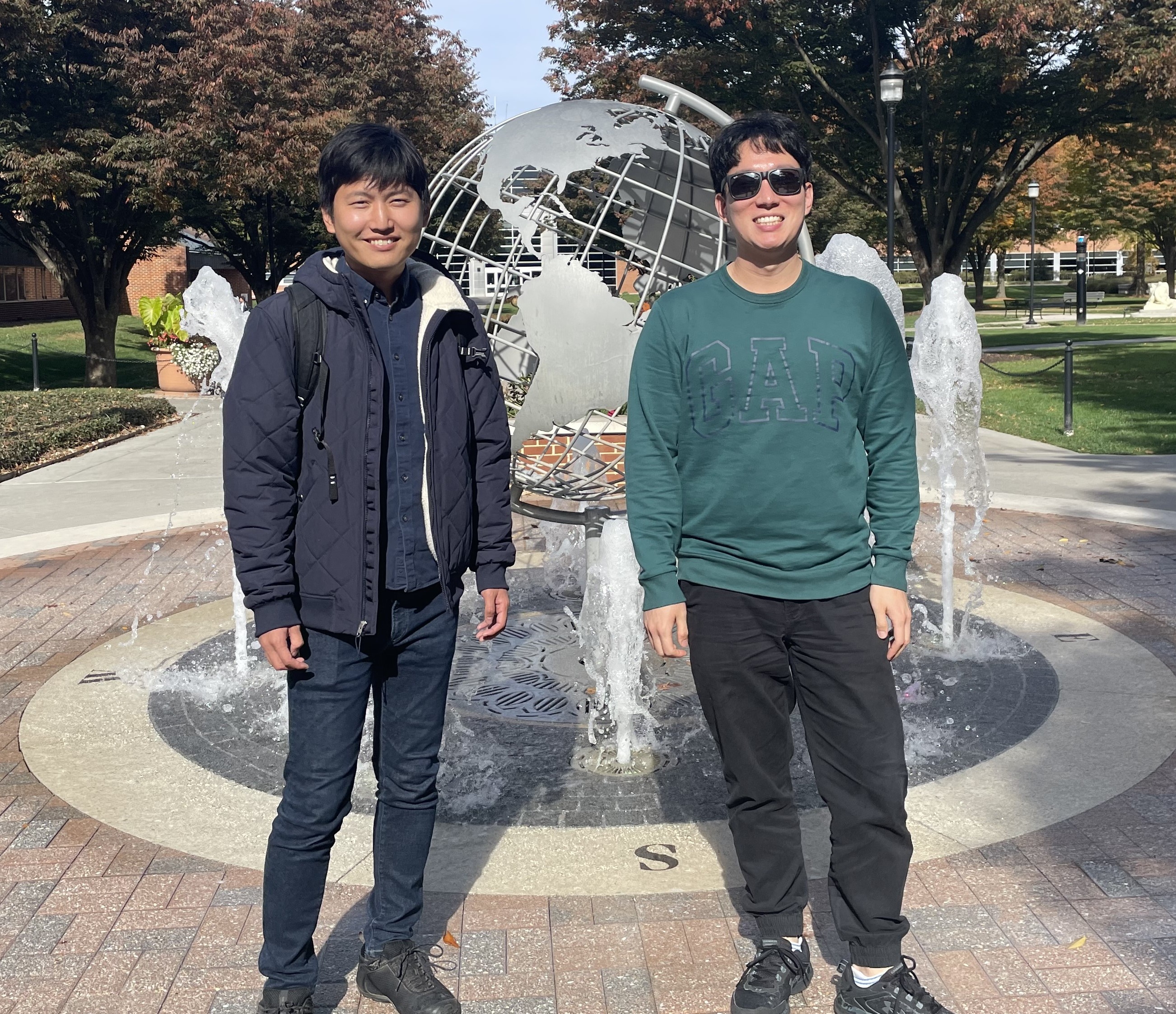 Two men standing in front of a globe statue