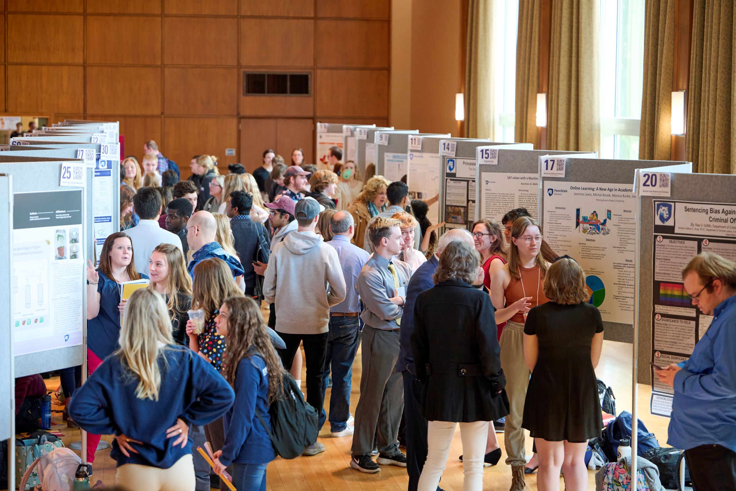 People mingling among research posters at the Undergraduate Exhibition