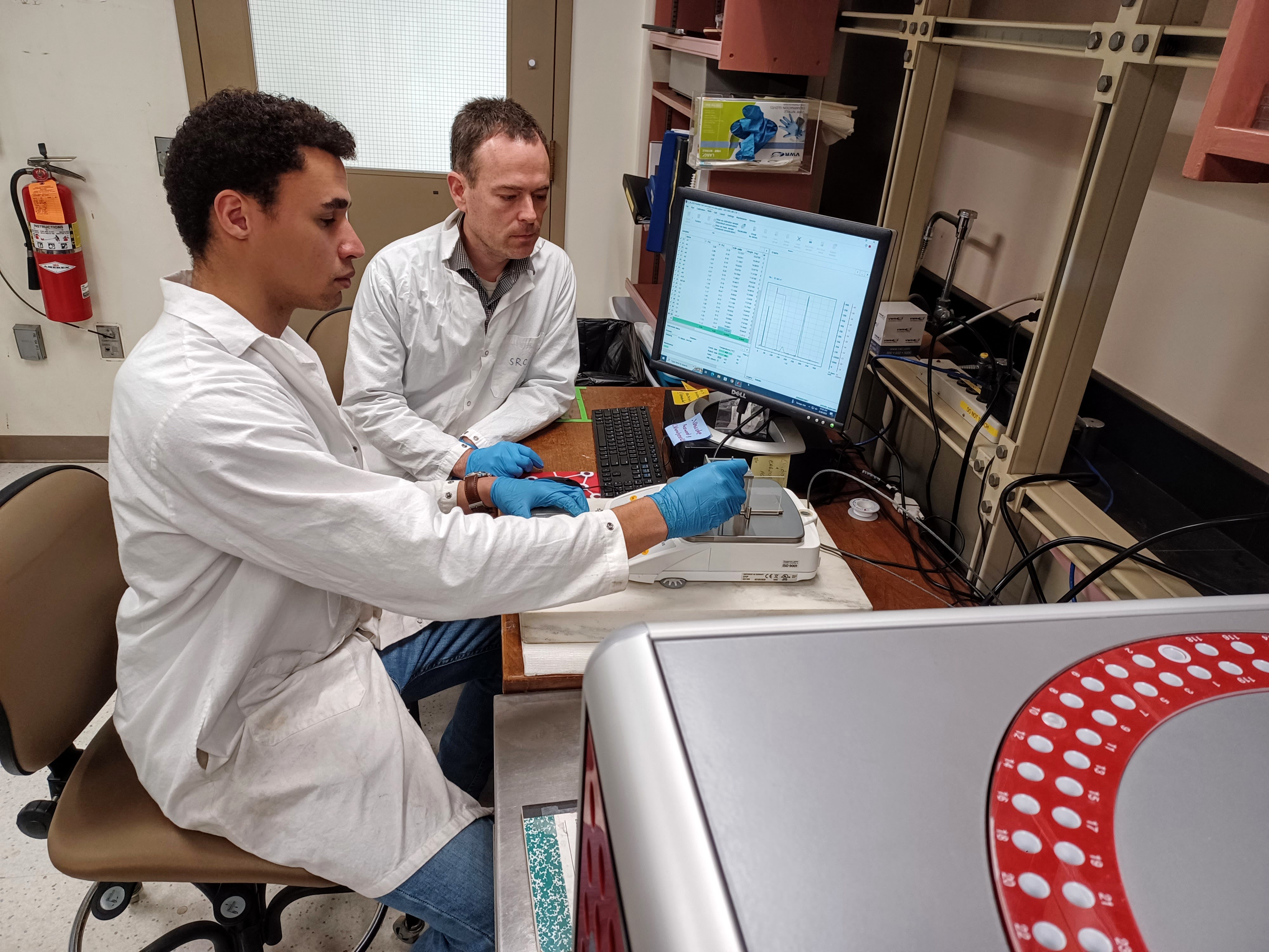 Lab manager trains an undergraduate student to use a piece of lab equipment