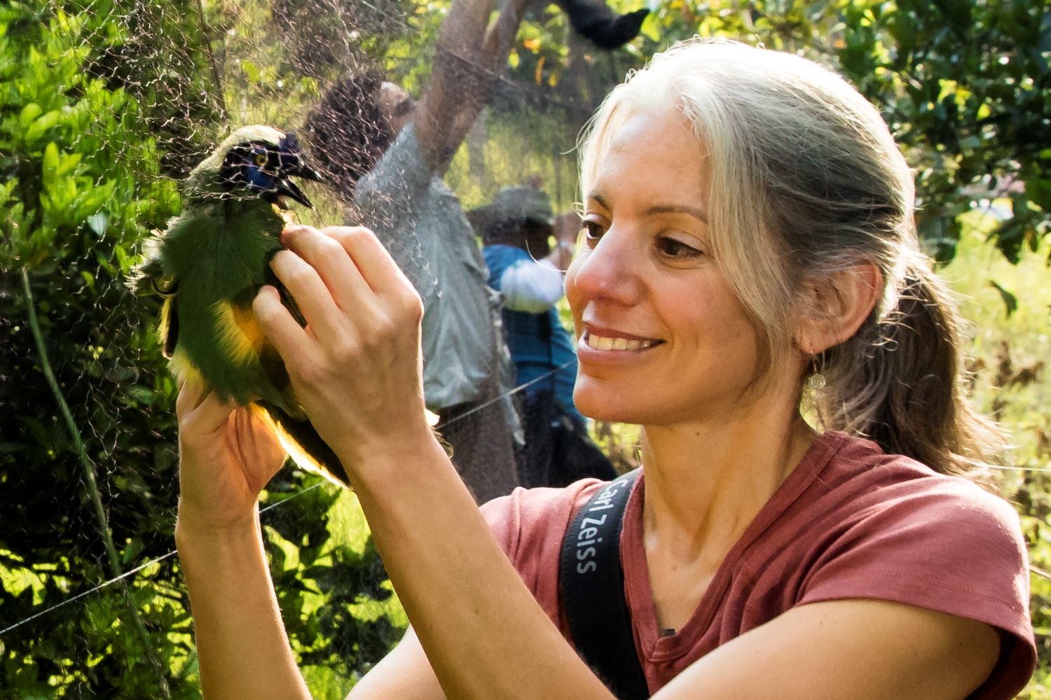 Woman looking at colorful bird in net