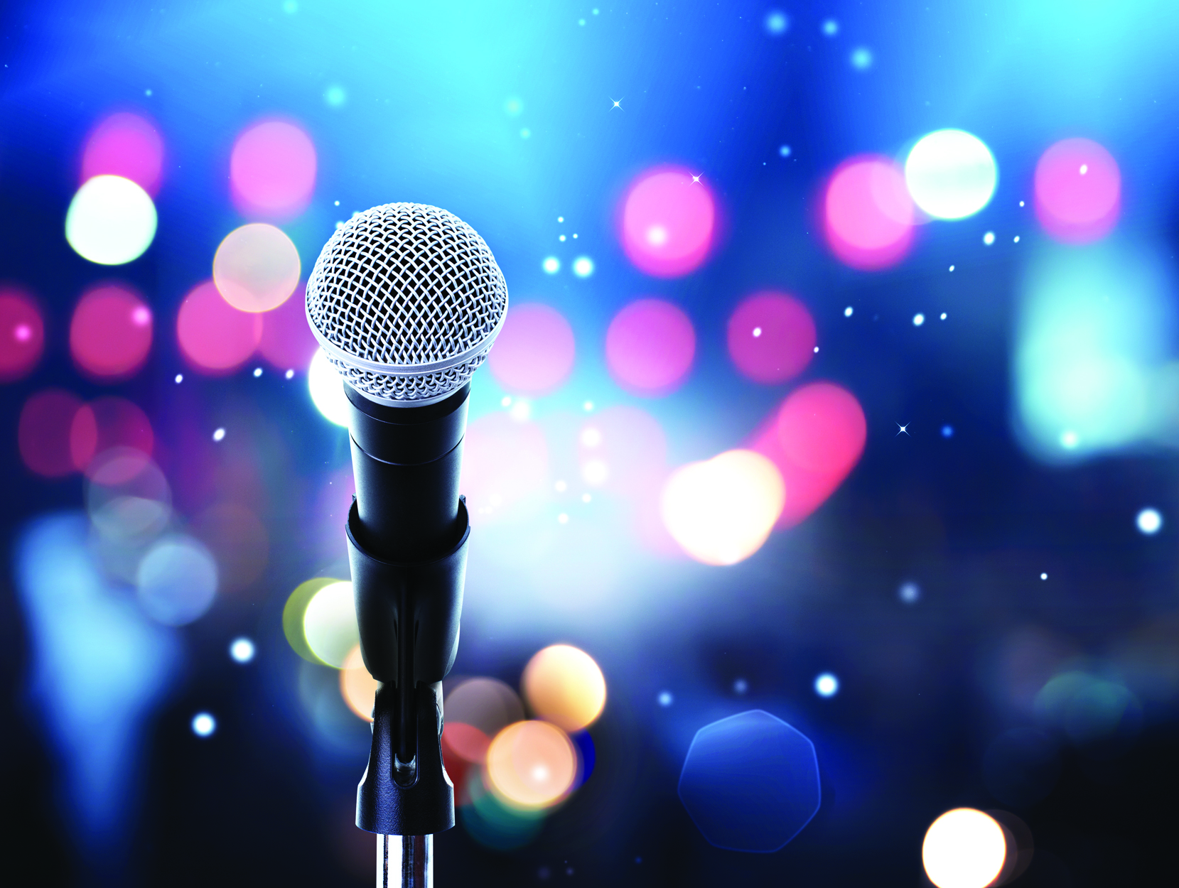 Image of microphone on stand with stage lights in the distance