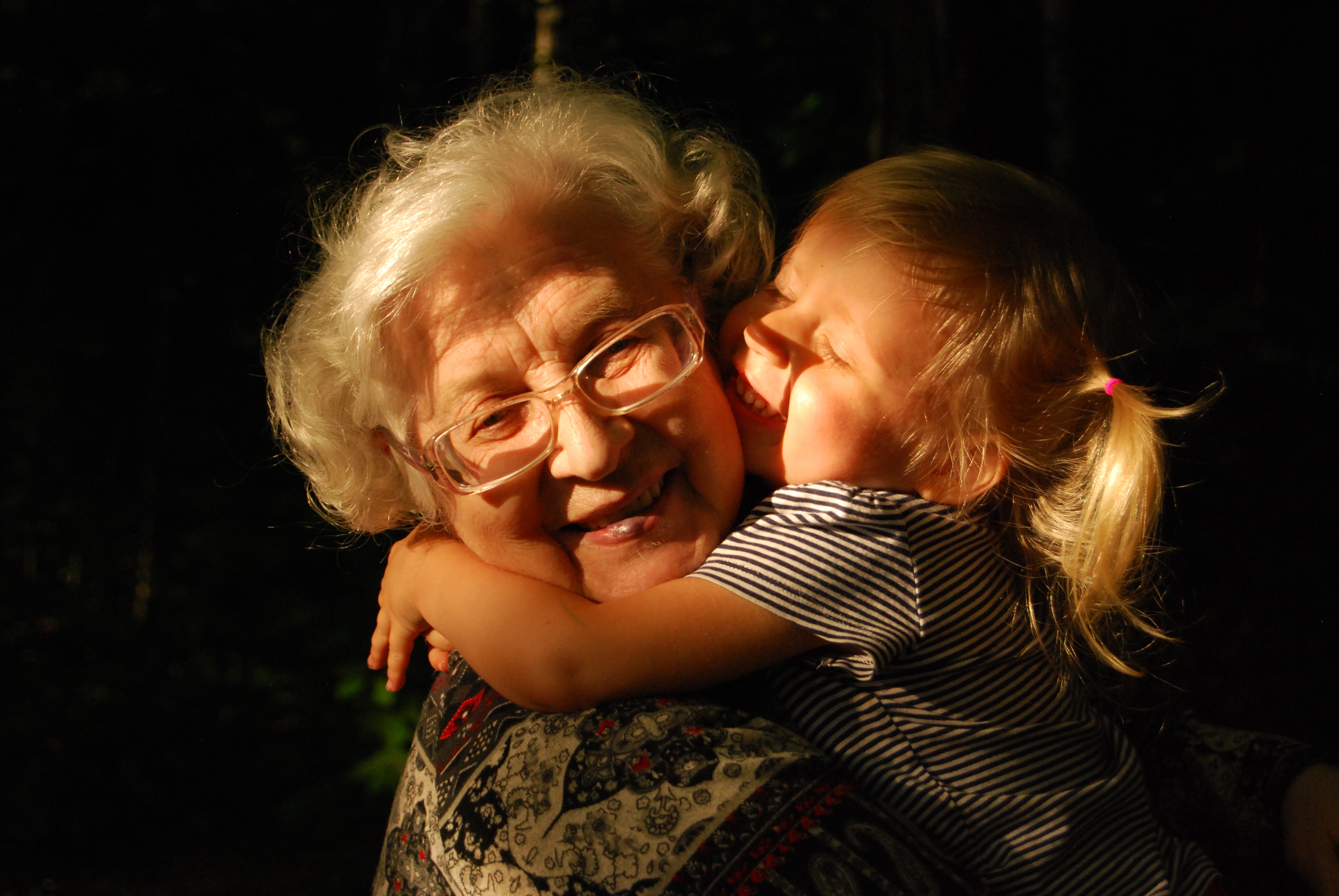 A young girl hugging her grandmother while they both smile