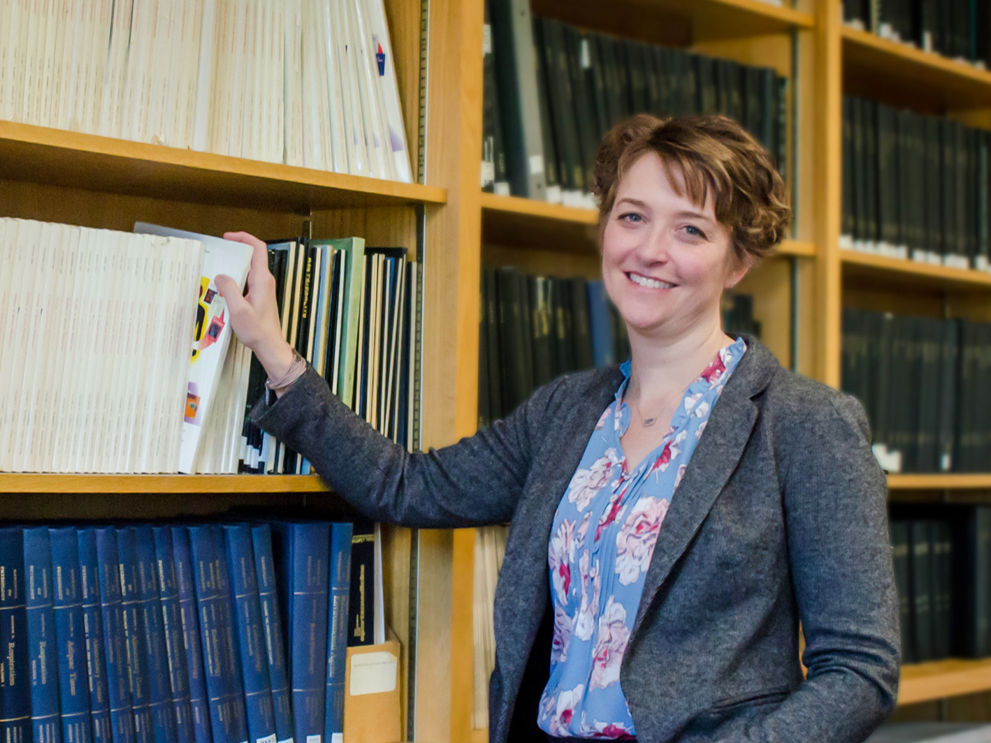 Lacy Alexander in front of a wall of journals