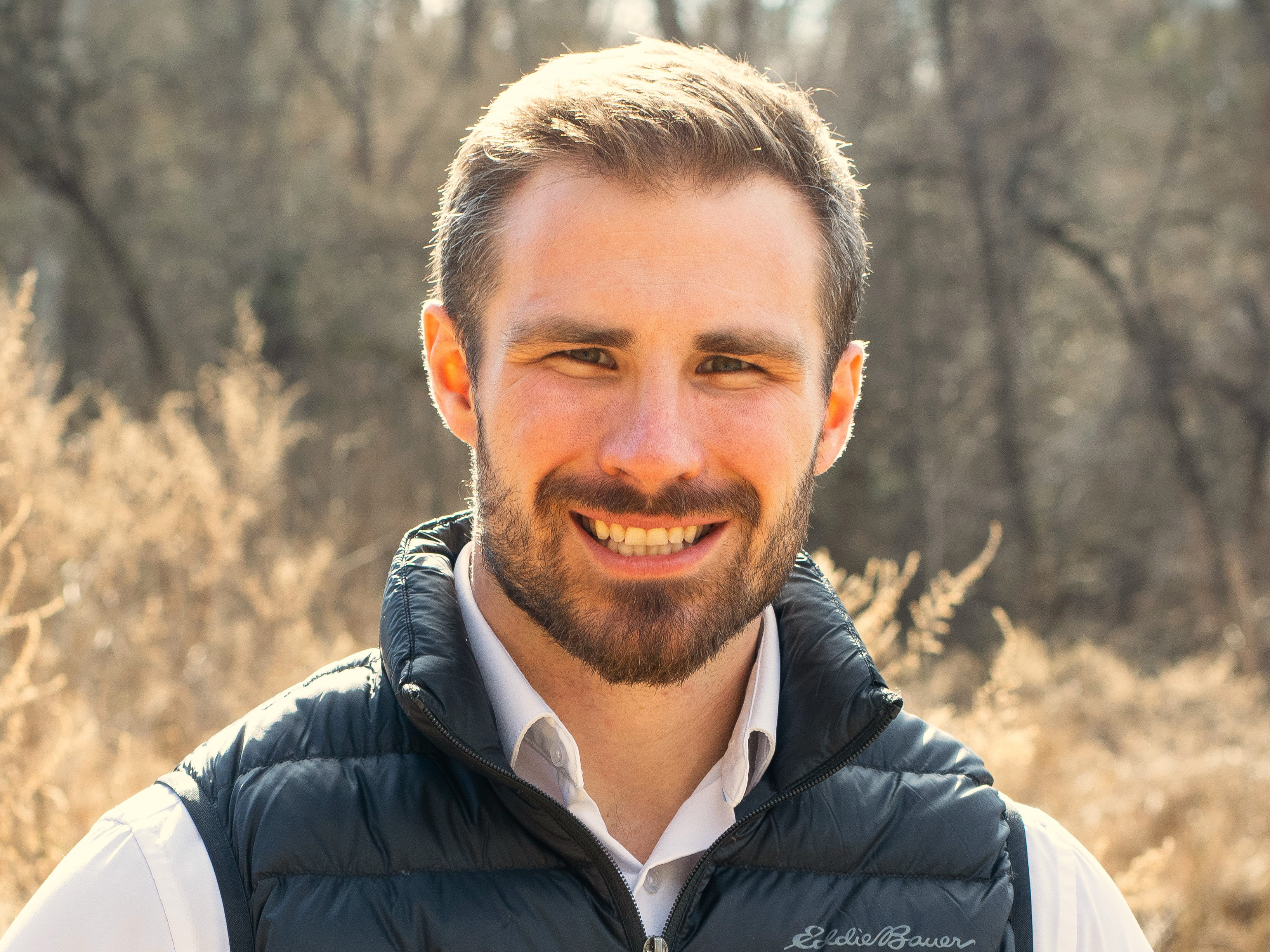 A head shot of a man standing outdoors.