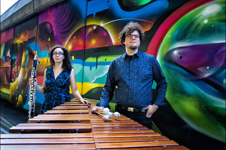 Man and woman in front of a vibrant mural 