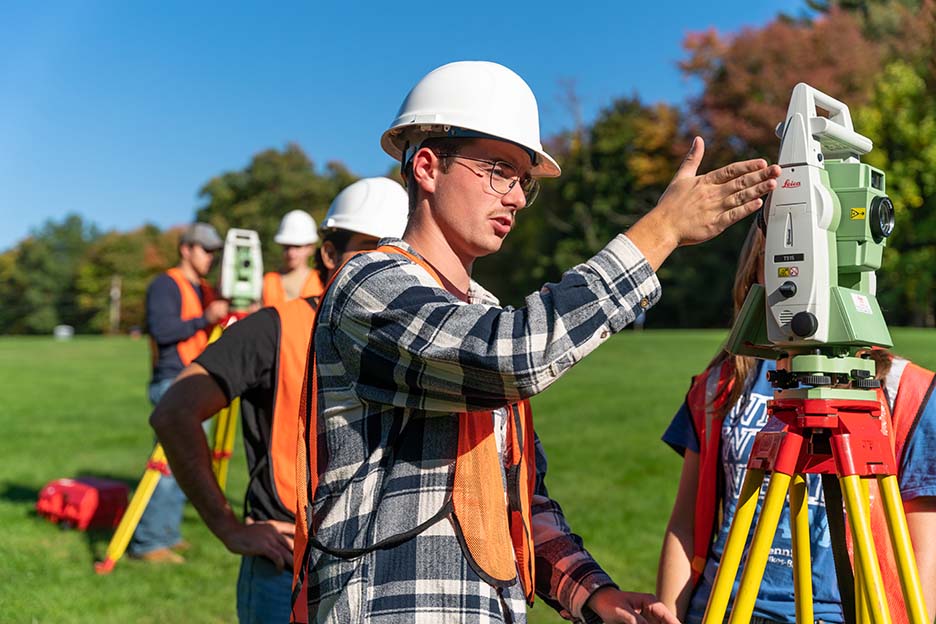 A student working with surveying equipment outdoors