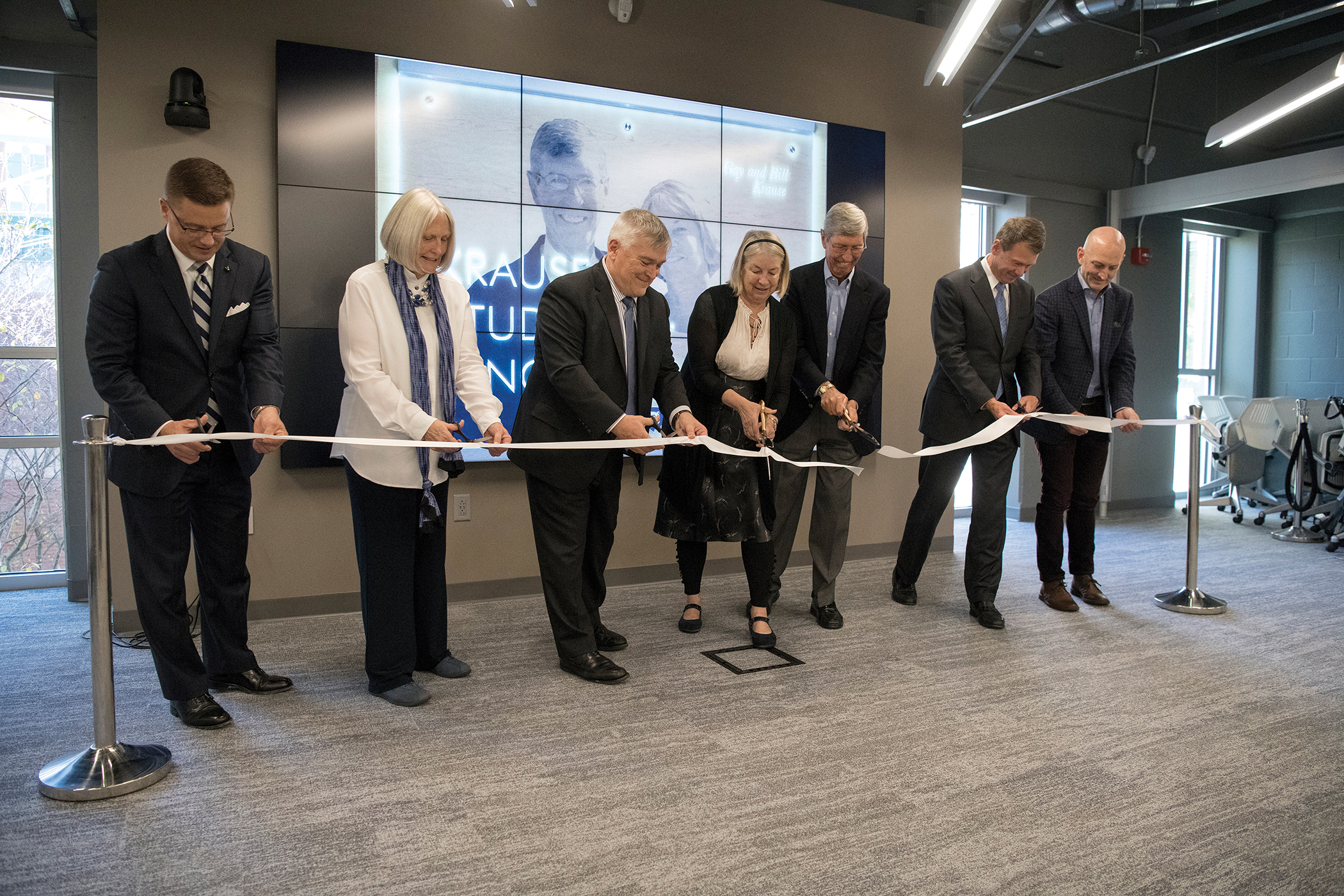 Several people cutting a ribbon at a ceremony