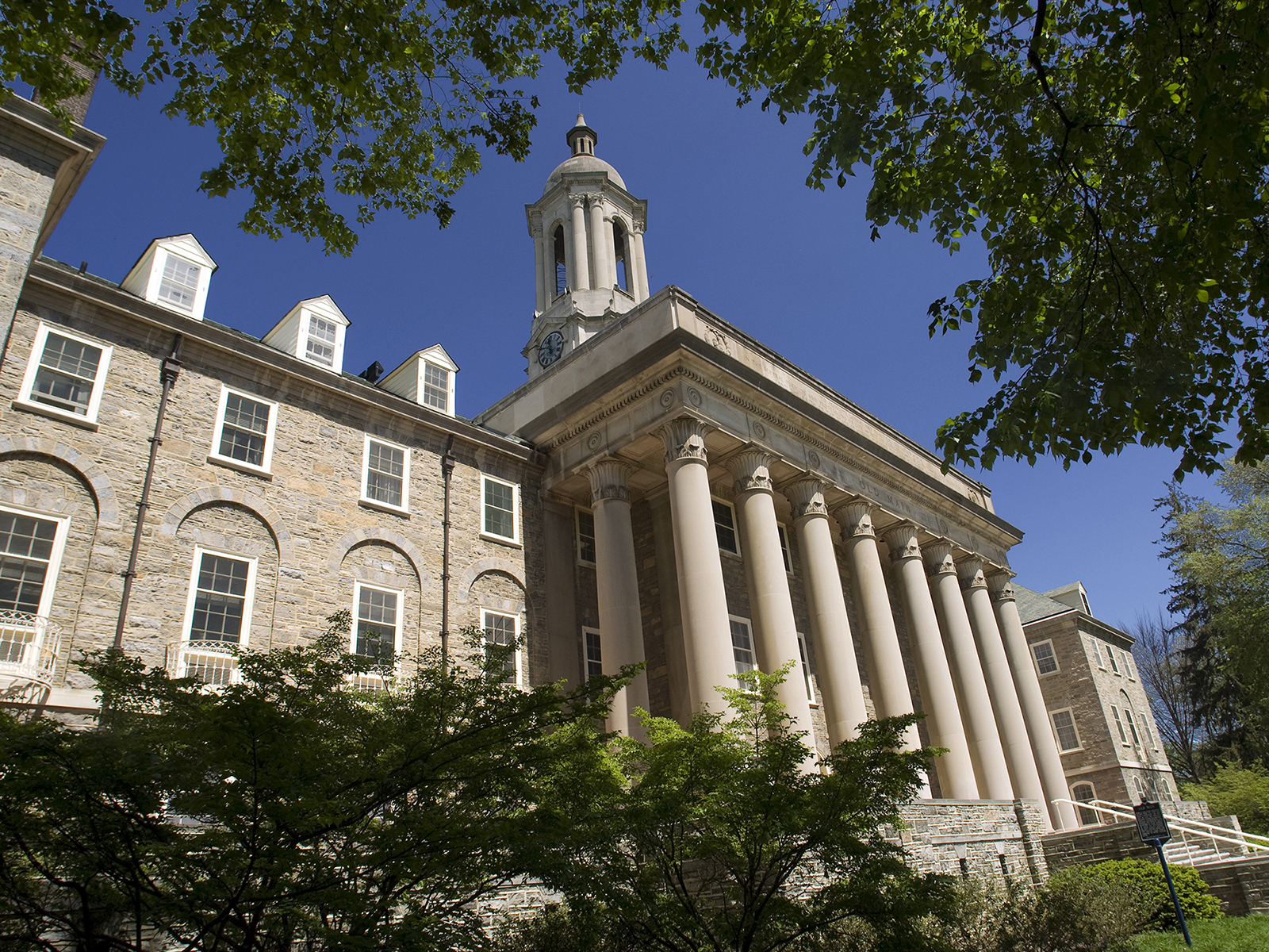 Old Main on a beautiful sunny day surrounded by green foliage and blue sky