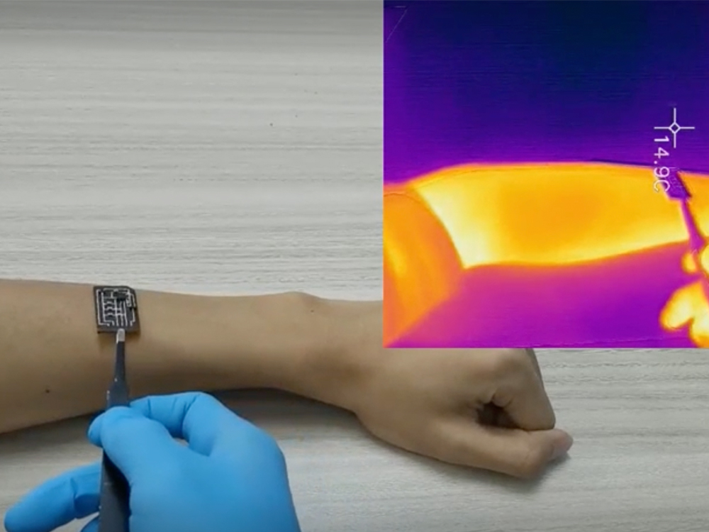 a gloved hand uses tweezers to place a small sensor on another person's forearm. A heat map of the forearm is shown in the upper right.