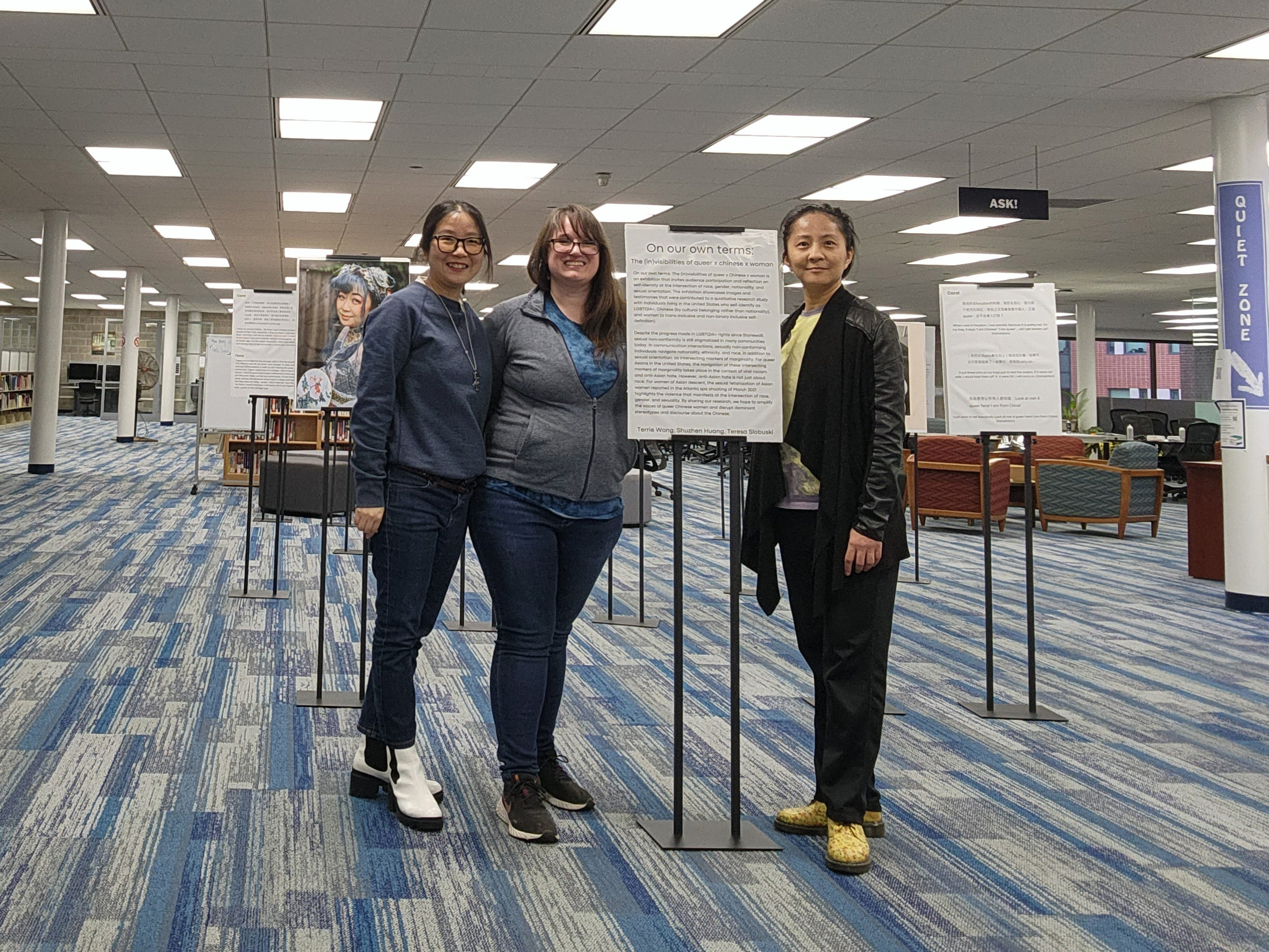 Three women standing in front of sign for exhibit