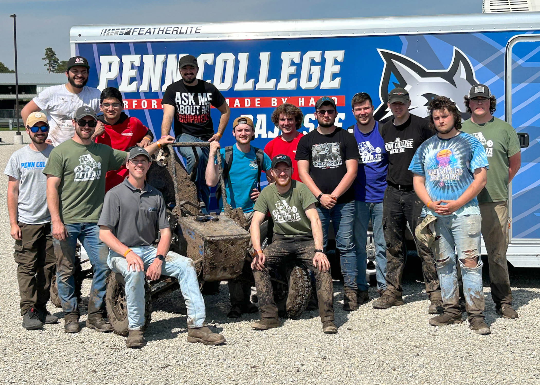 A group of people stand in front of a sign that says Penn College