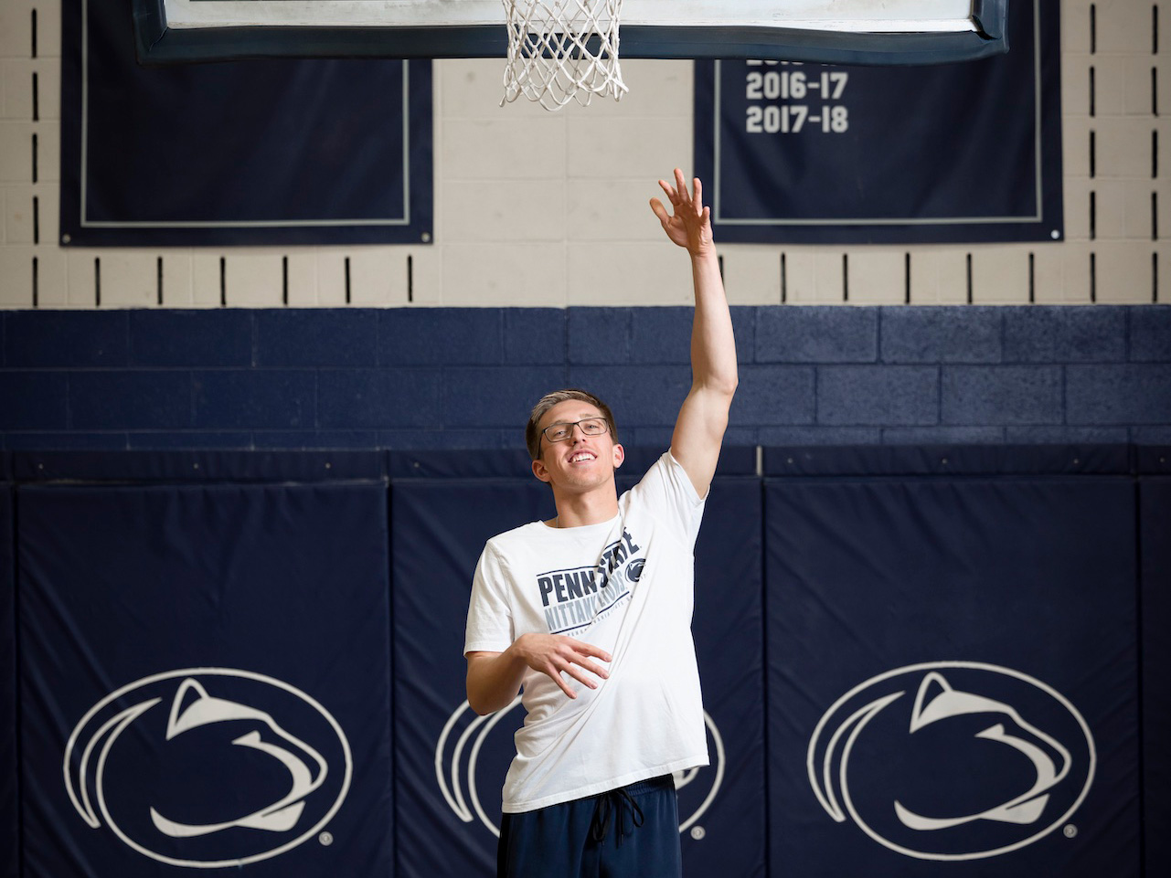 Man with arm up throwing basketball into net