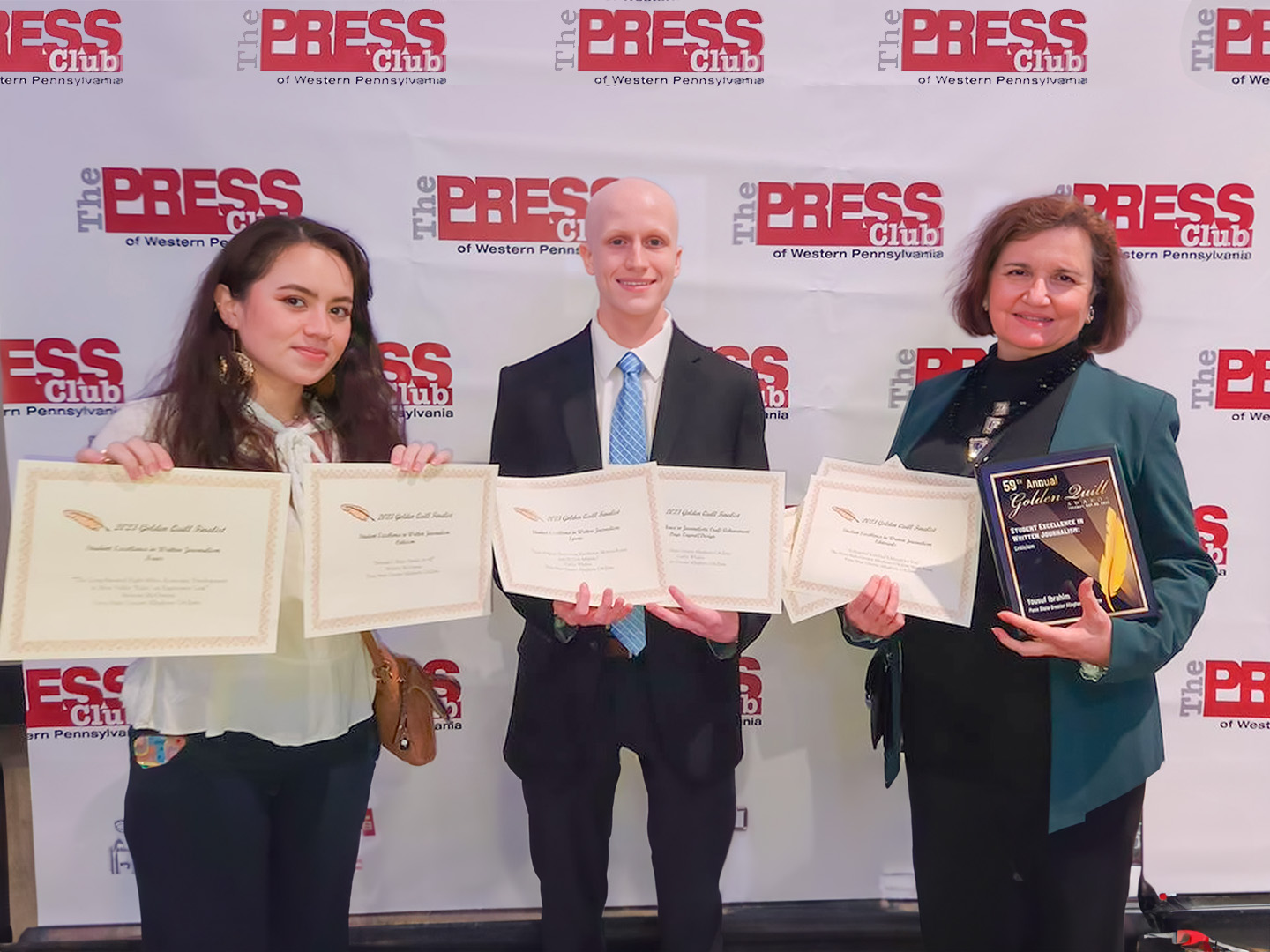 People smiling and holding certificates and a plaque 