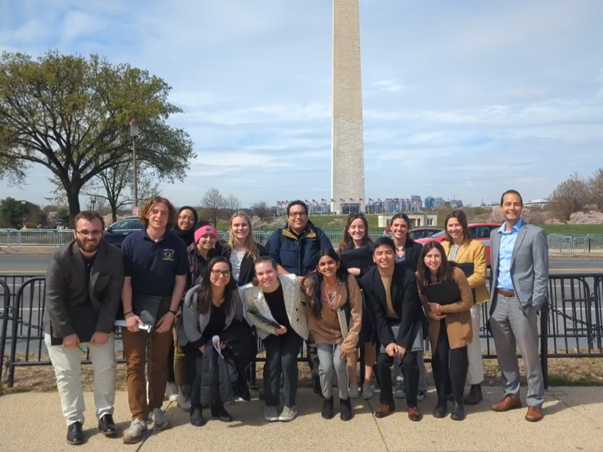 A group of students and their professors pose for a photo in front of the Washington monument