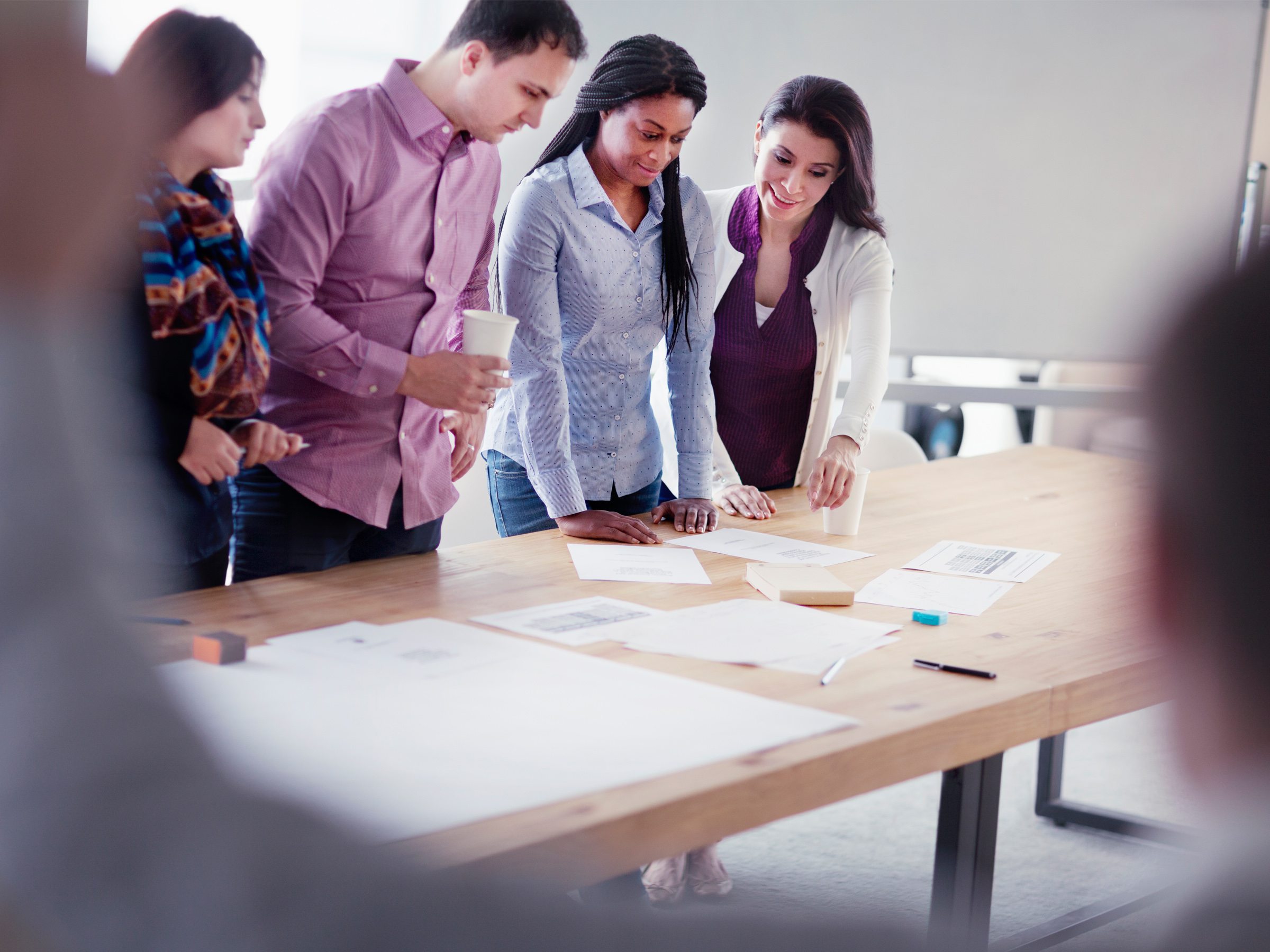 People lean over a desk looking at papers.