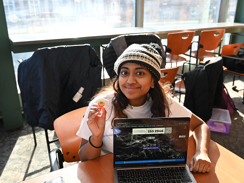 An individual poses at a table with a laptop computer.