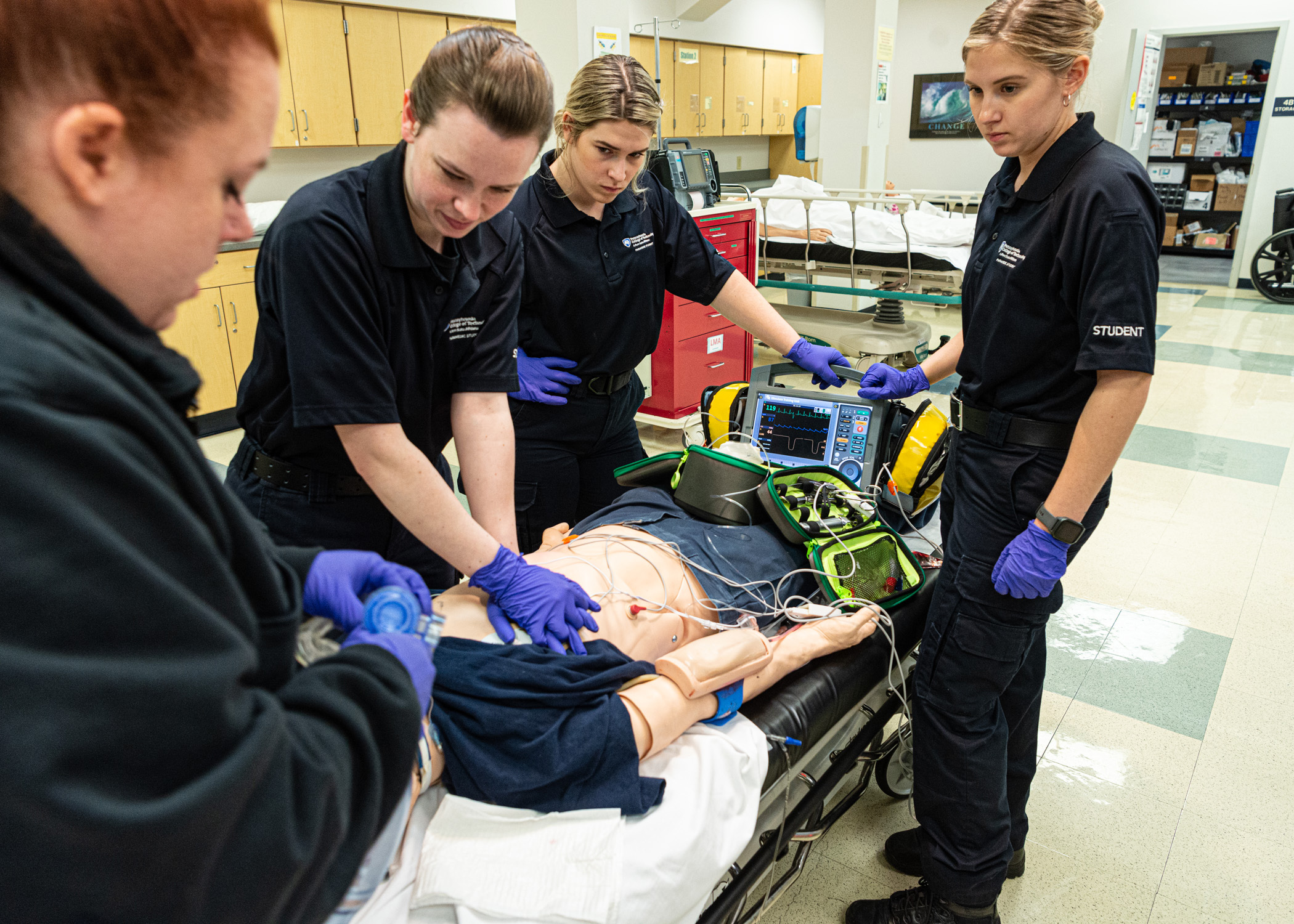 Several people stand around a medical manikin on a table