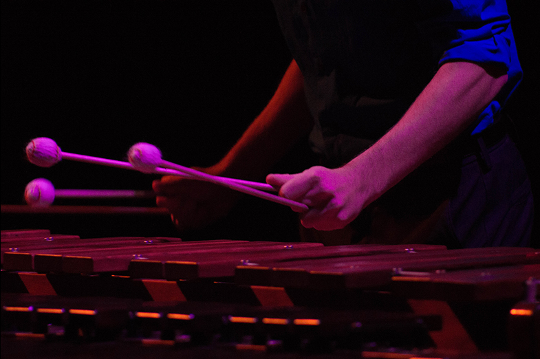 Stage performance shot of hands holding mallets above a xylophone. 