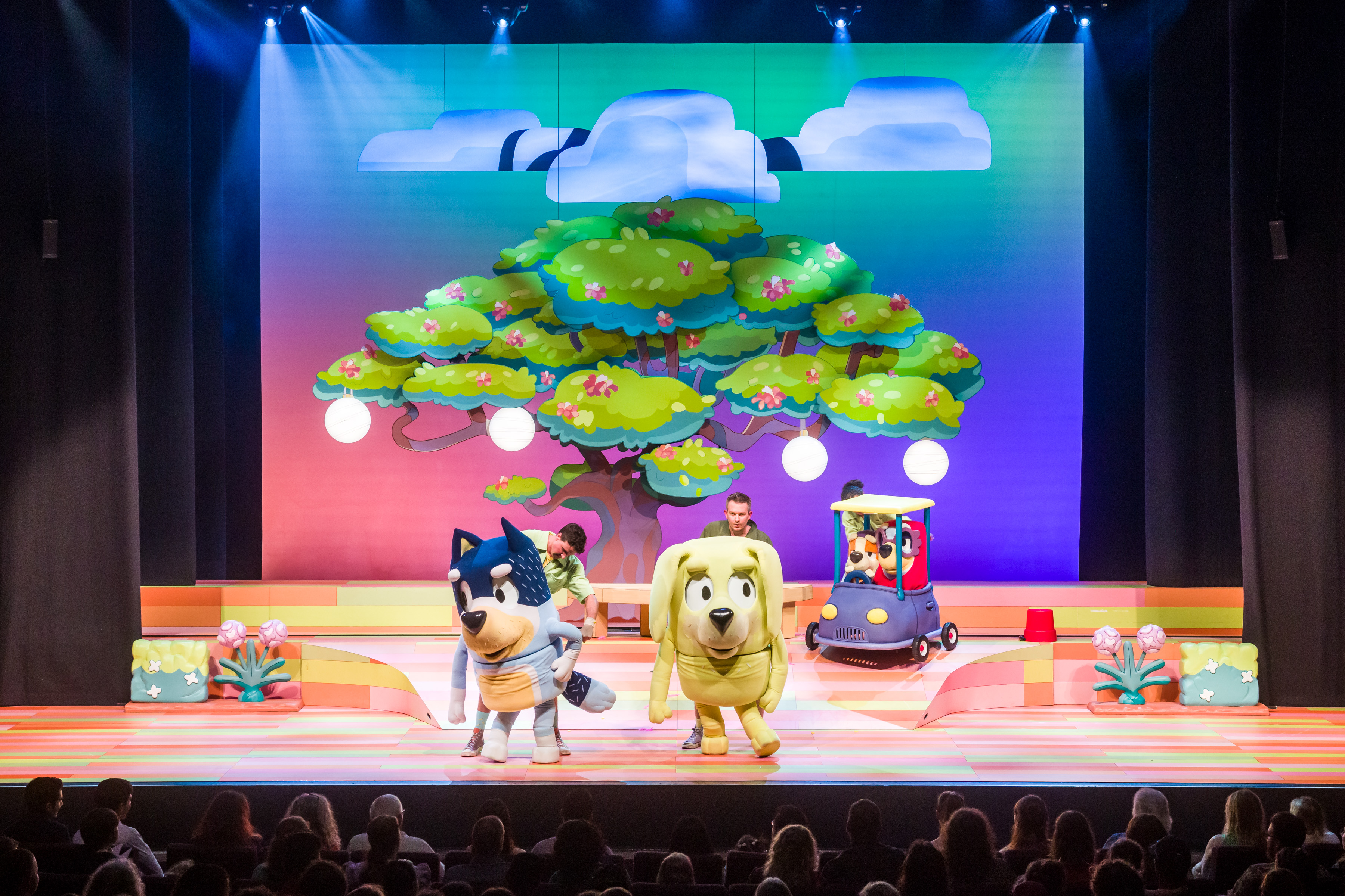 Two oversized cartoonish dog puppets are shown standing center stage.