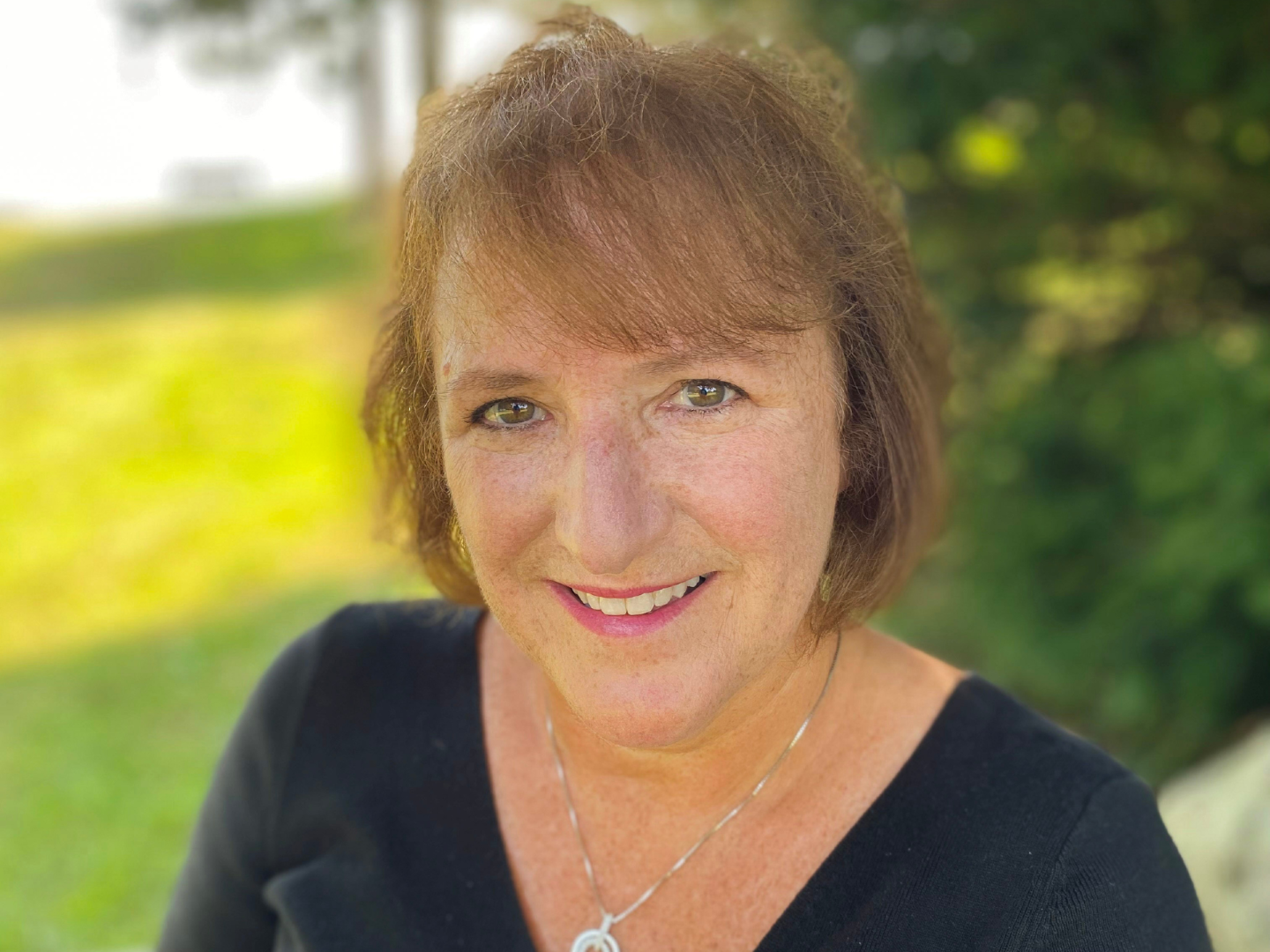 headshot of short-haired person in outdoor setting