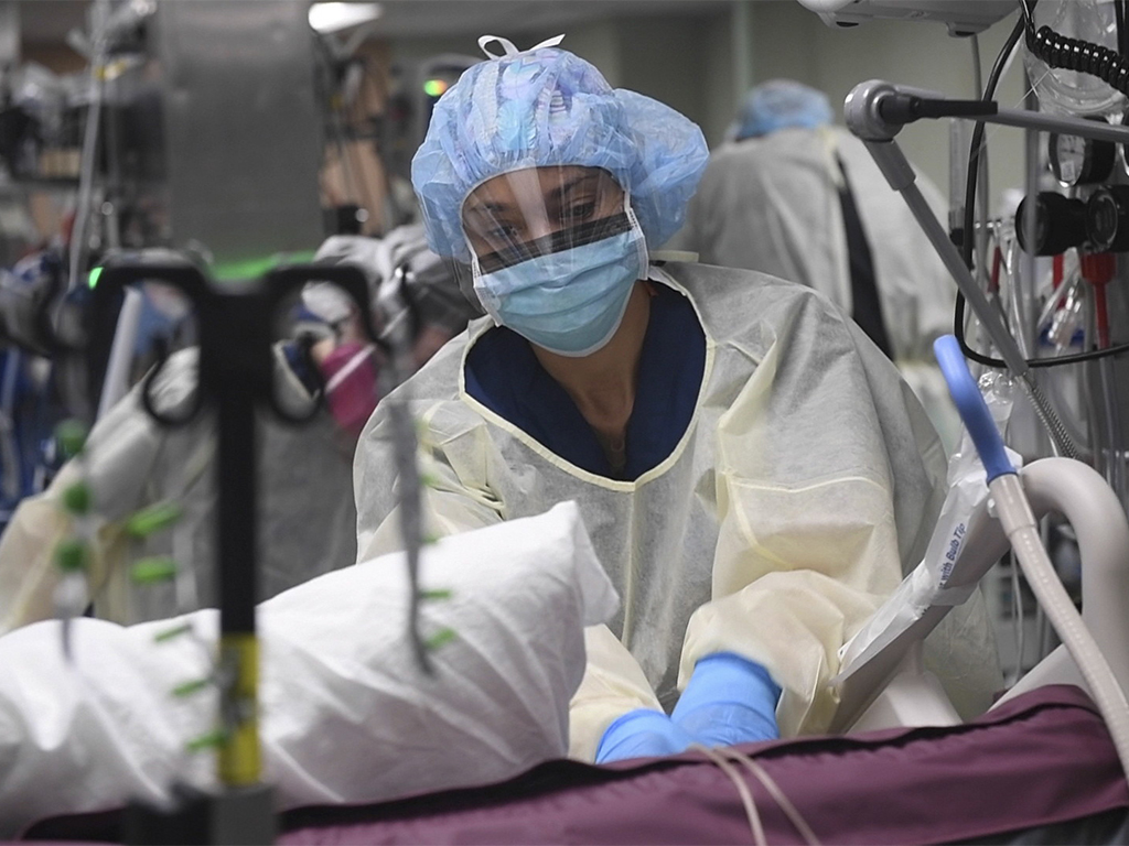  A nurse preparing a COVID-19 patient for a procedure in intensive care