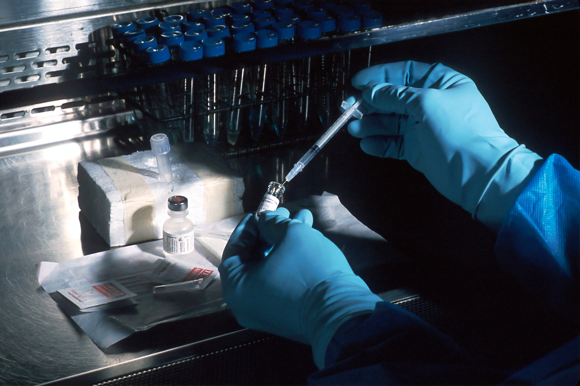 gloved hands holding syringe next to drug