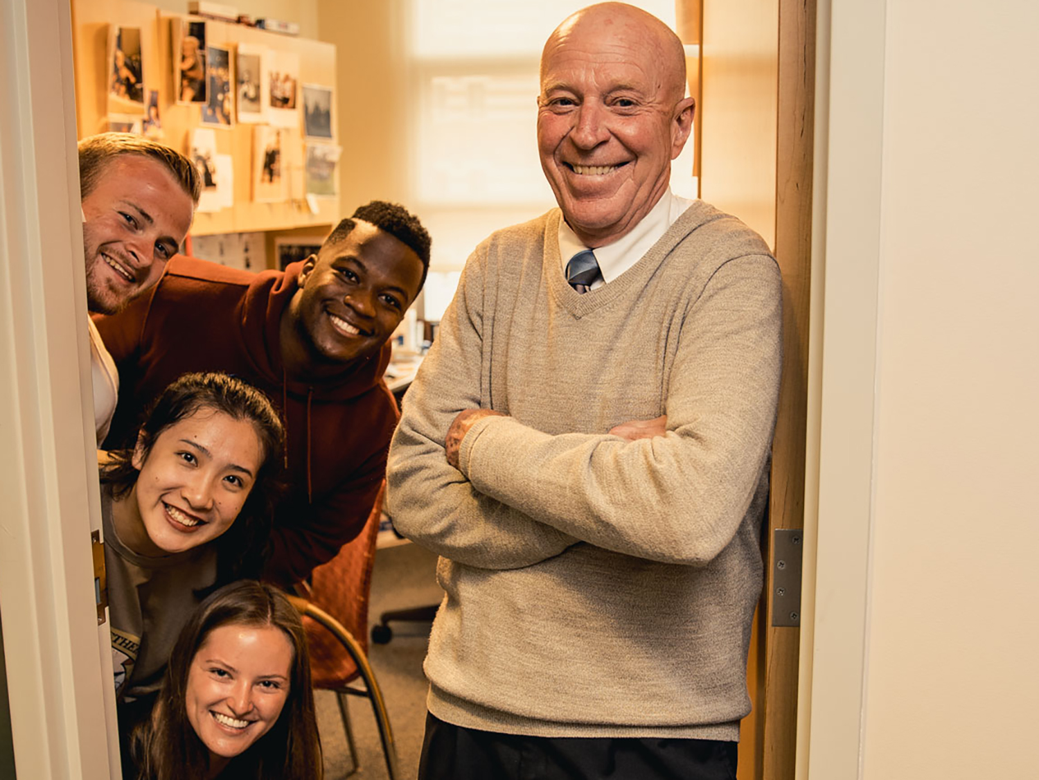 A photo of Bob Novack and four students smiling in the doorway to his office.