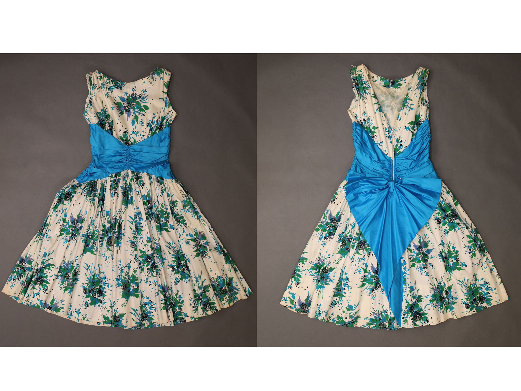 A white dress with blue and green flowers and a bright blue sash, style of the 1950s or 1960s