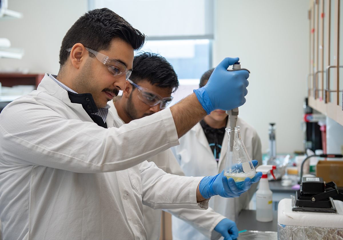 A researcher uses a pipette and a beaker in a lab.