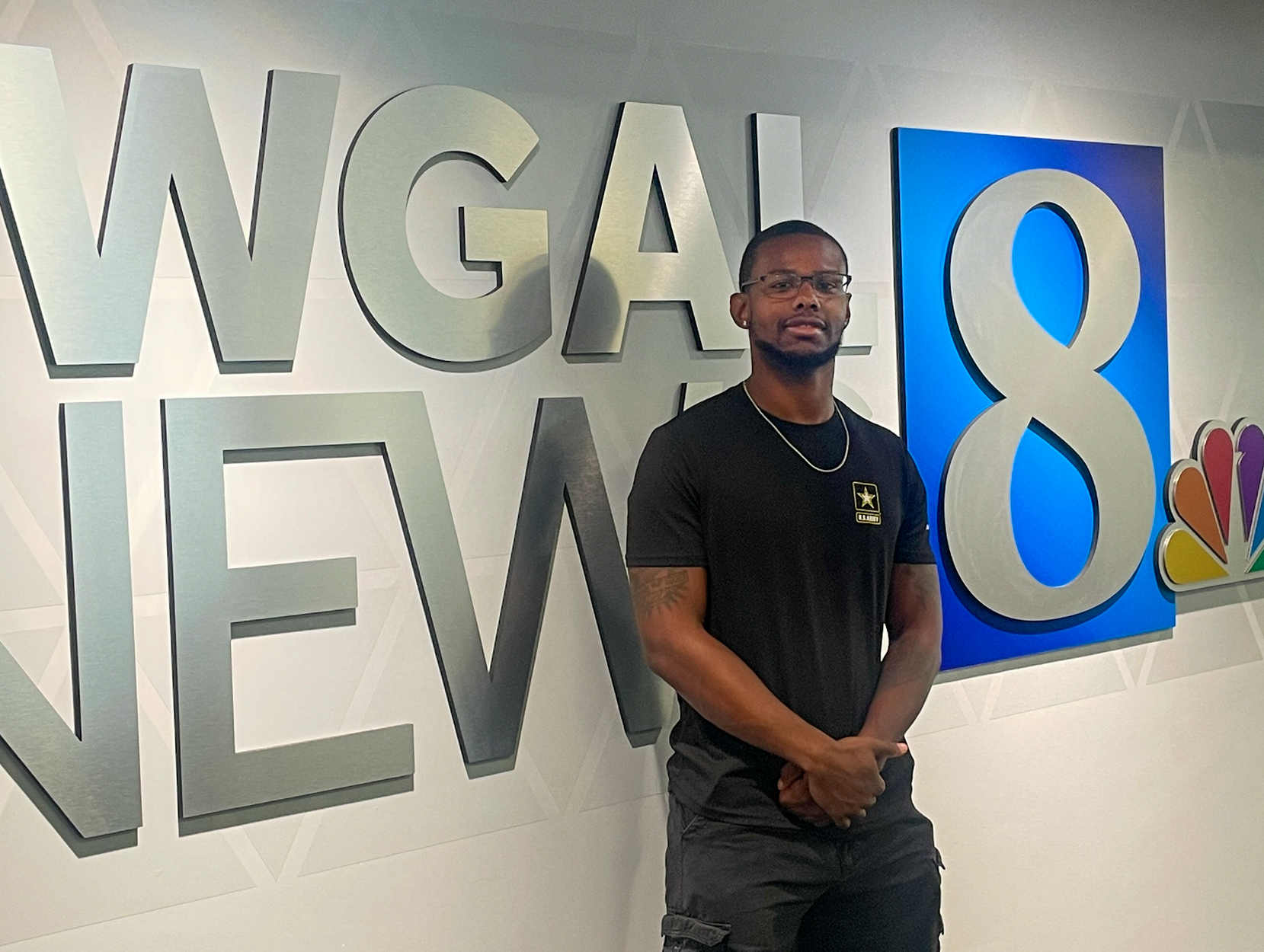 Ashon Calhoun stands in front of a wall with WGAL News 8 logo