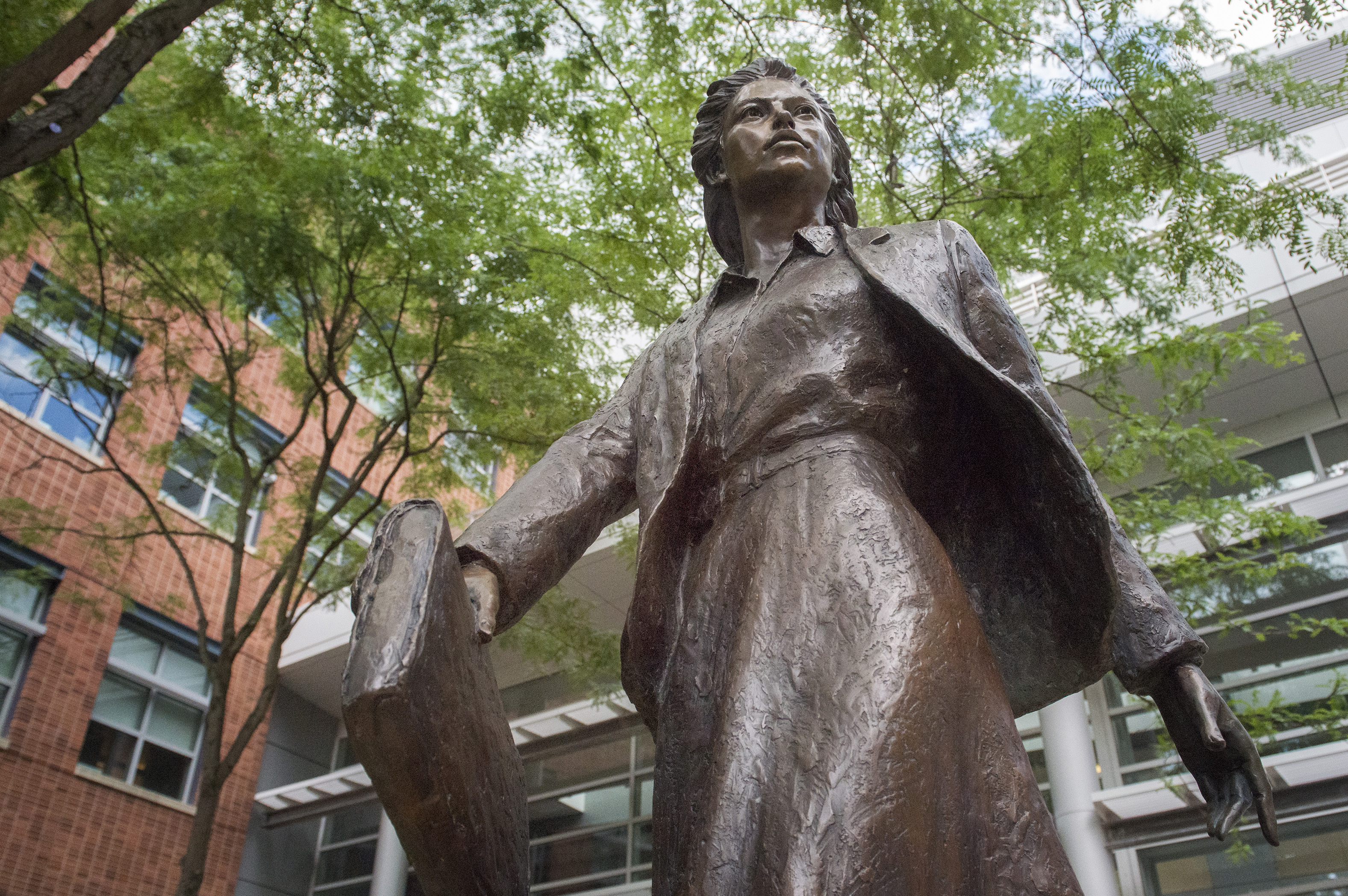 A bronze statue of a woman wearing a business suit and carrying a briefcase, outside