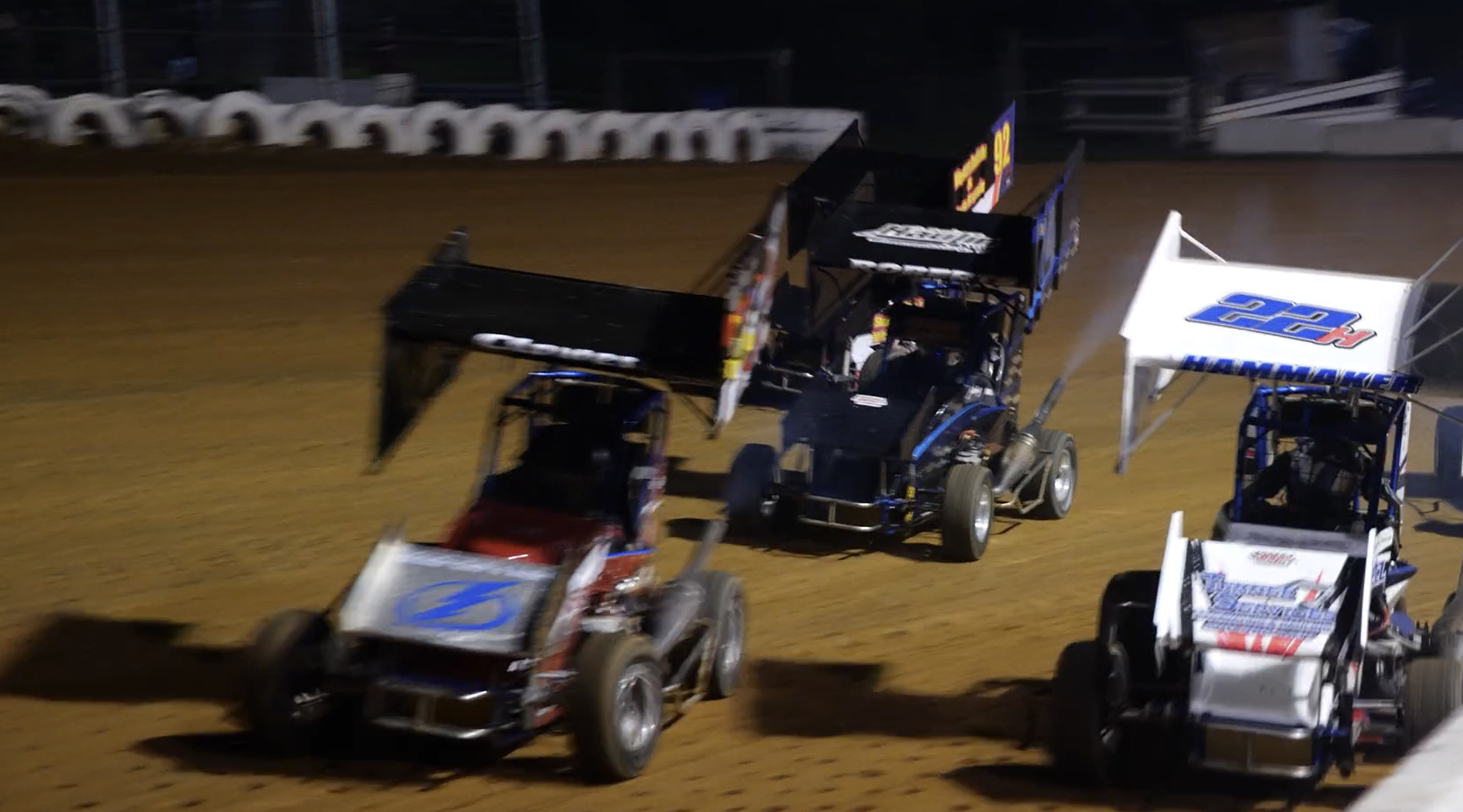 Three sprint cars race around a track