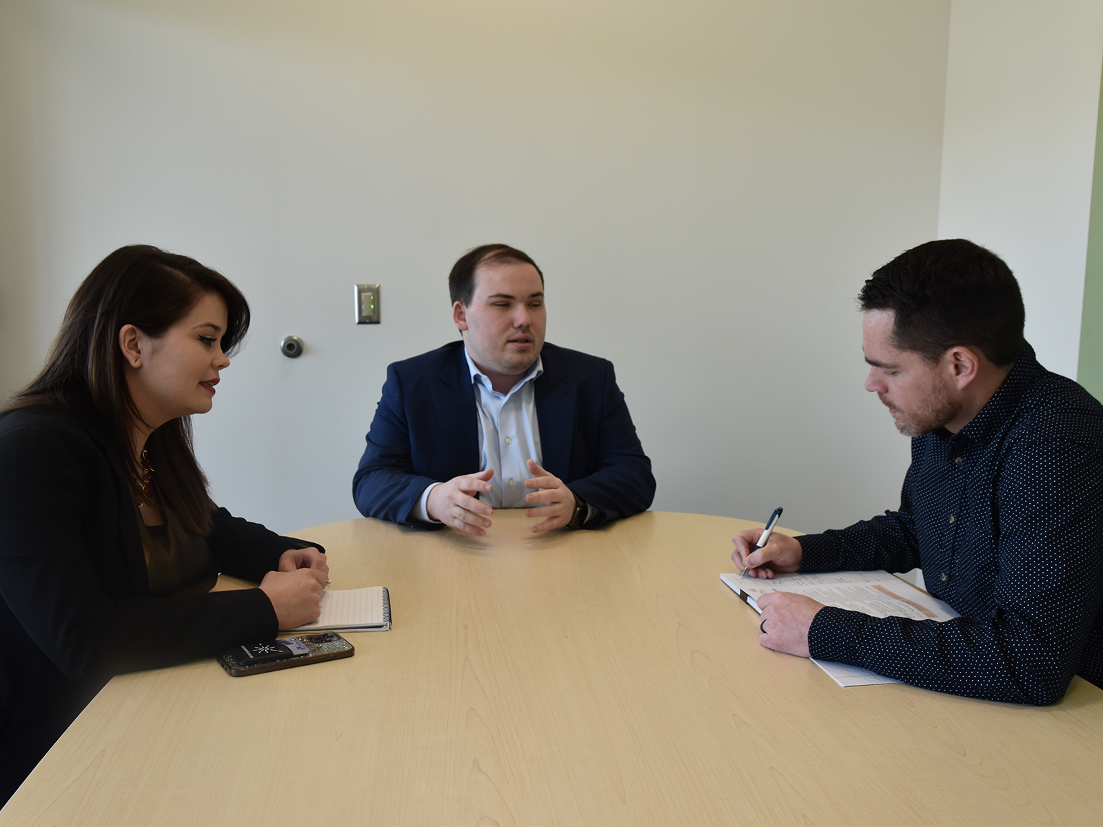 Three people have a discussion around a table