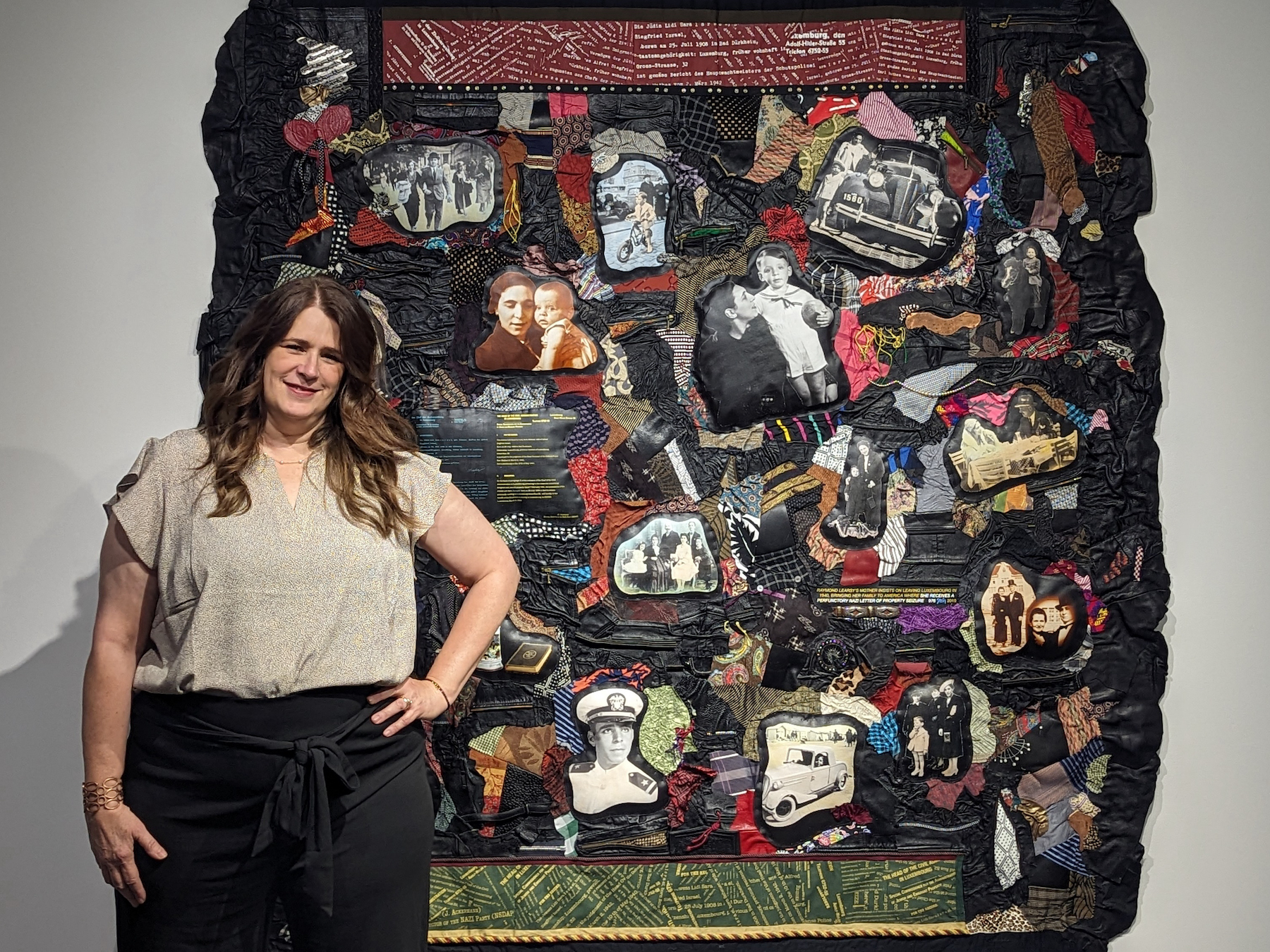 woman standing next to large multimedia art piece on wall