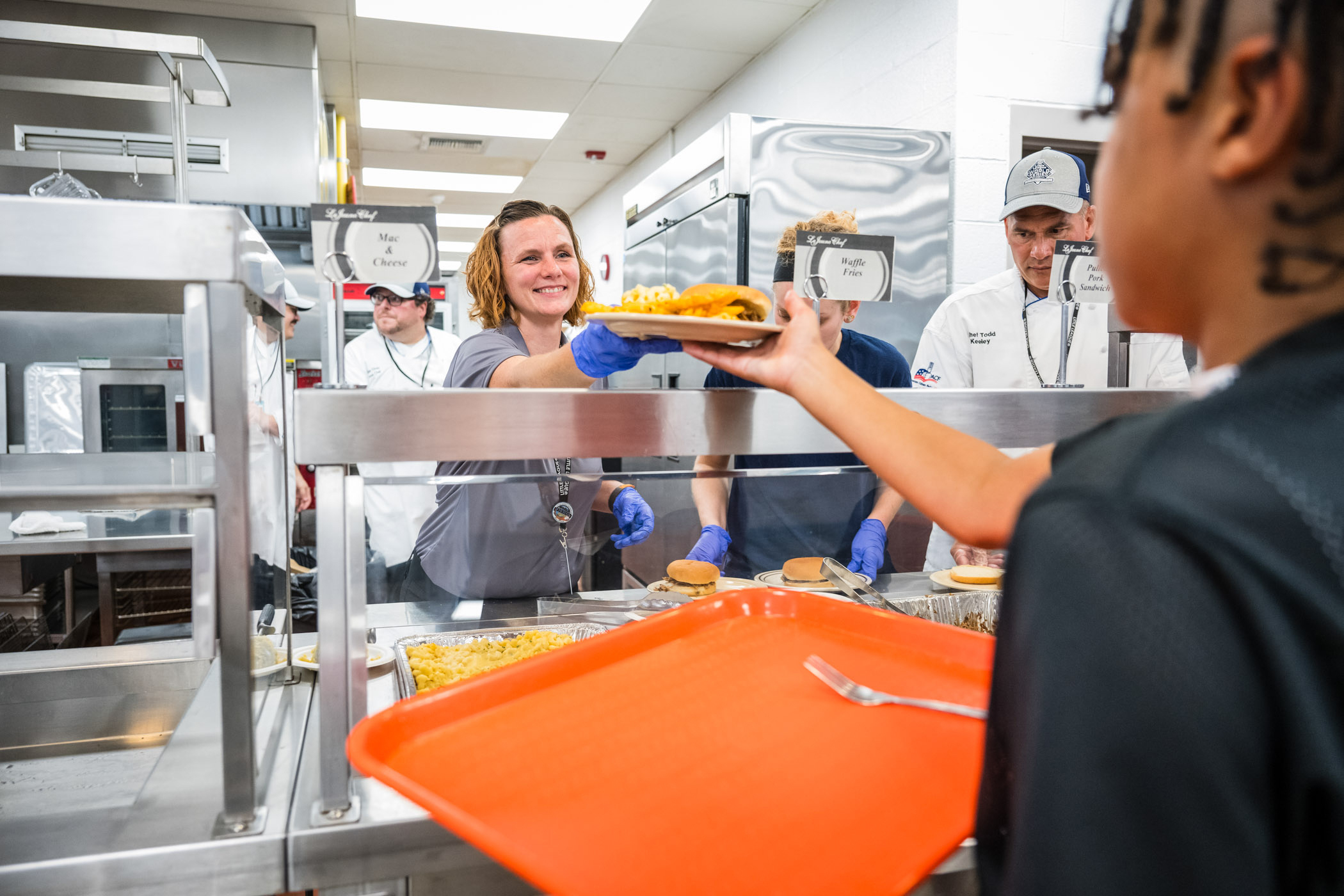 A person serves a plate of food to a baseball competitor. 