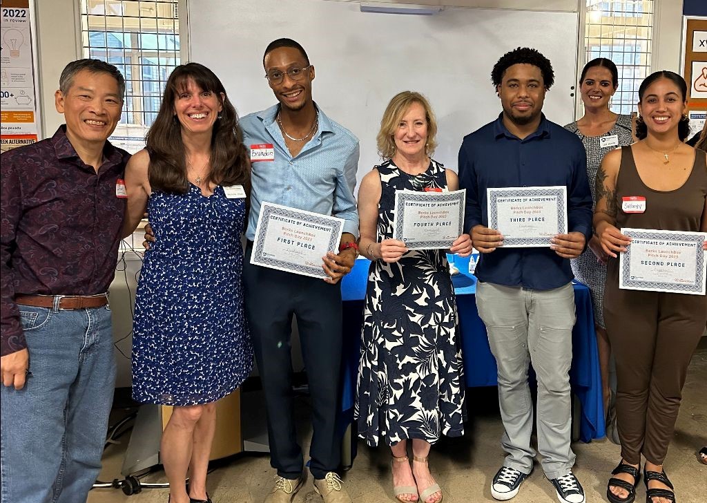 Seven people pose for a photo holding certificates