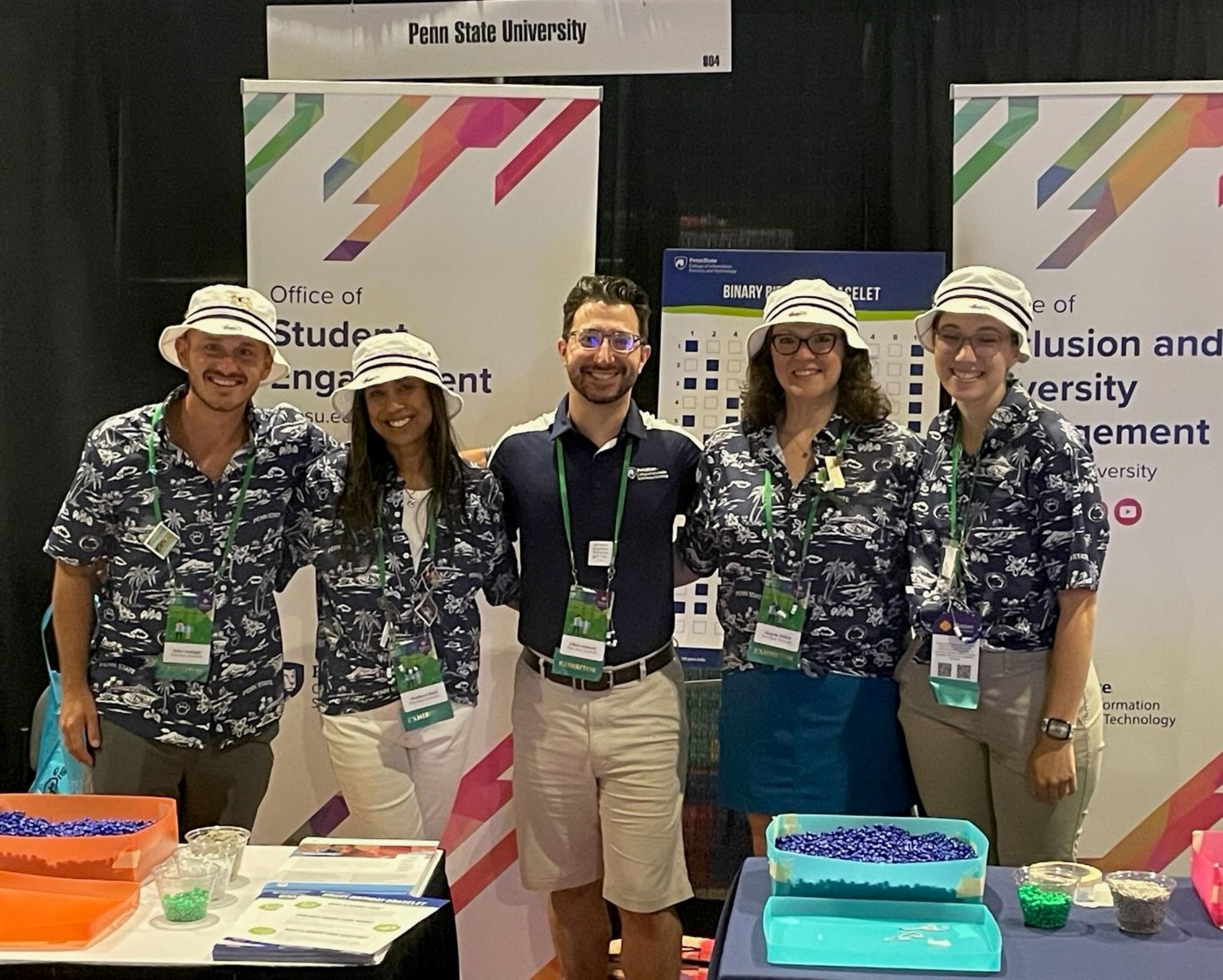 five convention attendees pose at their booth