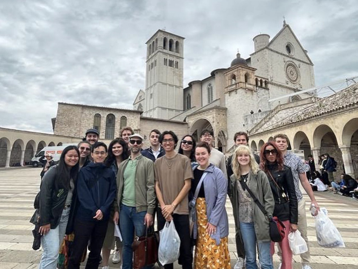 A group of people stand in front of an Italian building. 