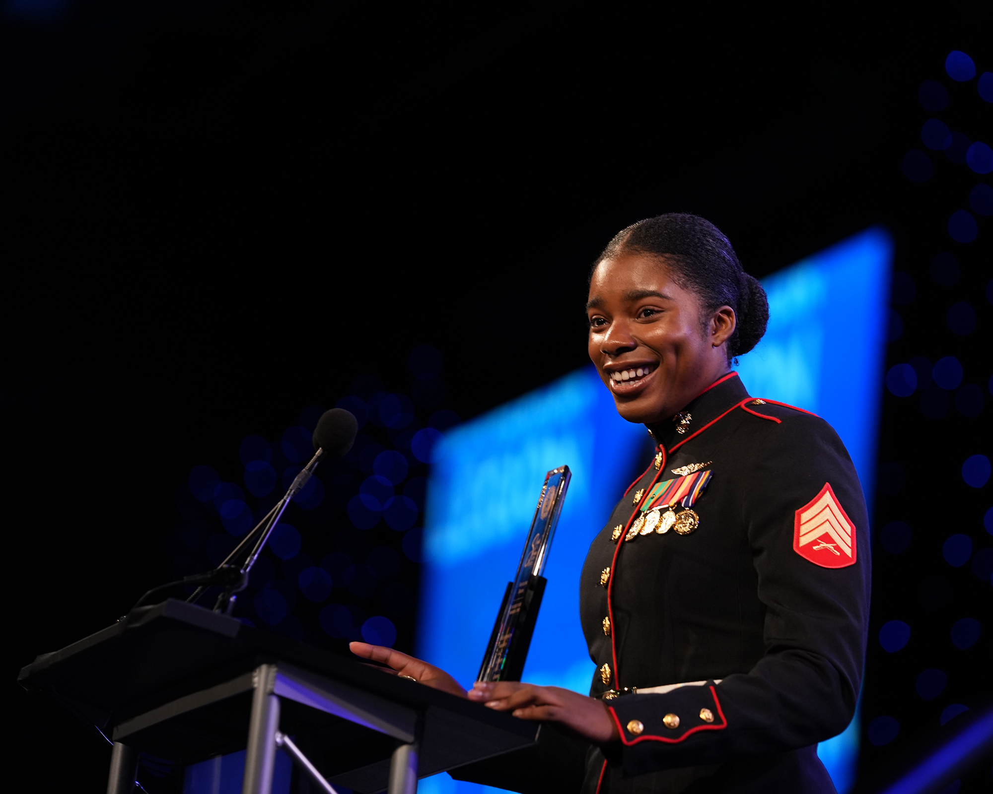 A woman wearing a military uniform speaks at a podium.