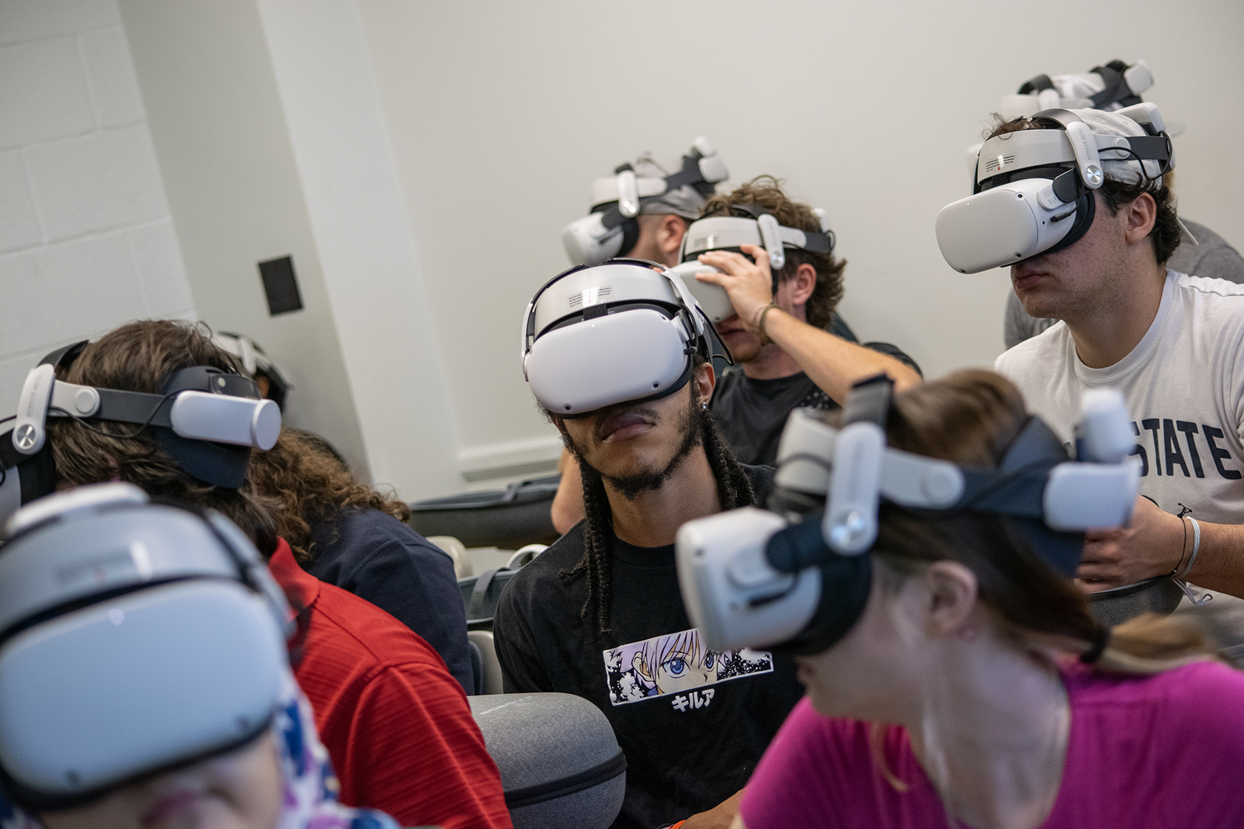 Students in a classroom wear white reality headsets that cover their eyes