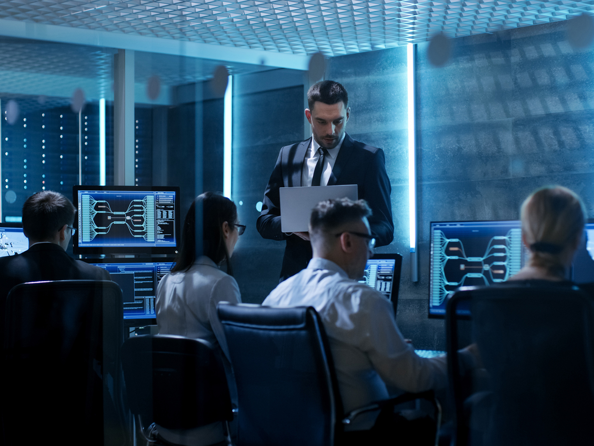 A group of people work on computers in a technological office.