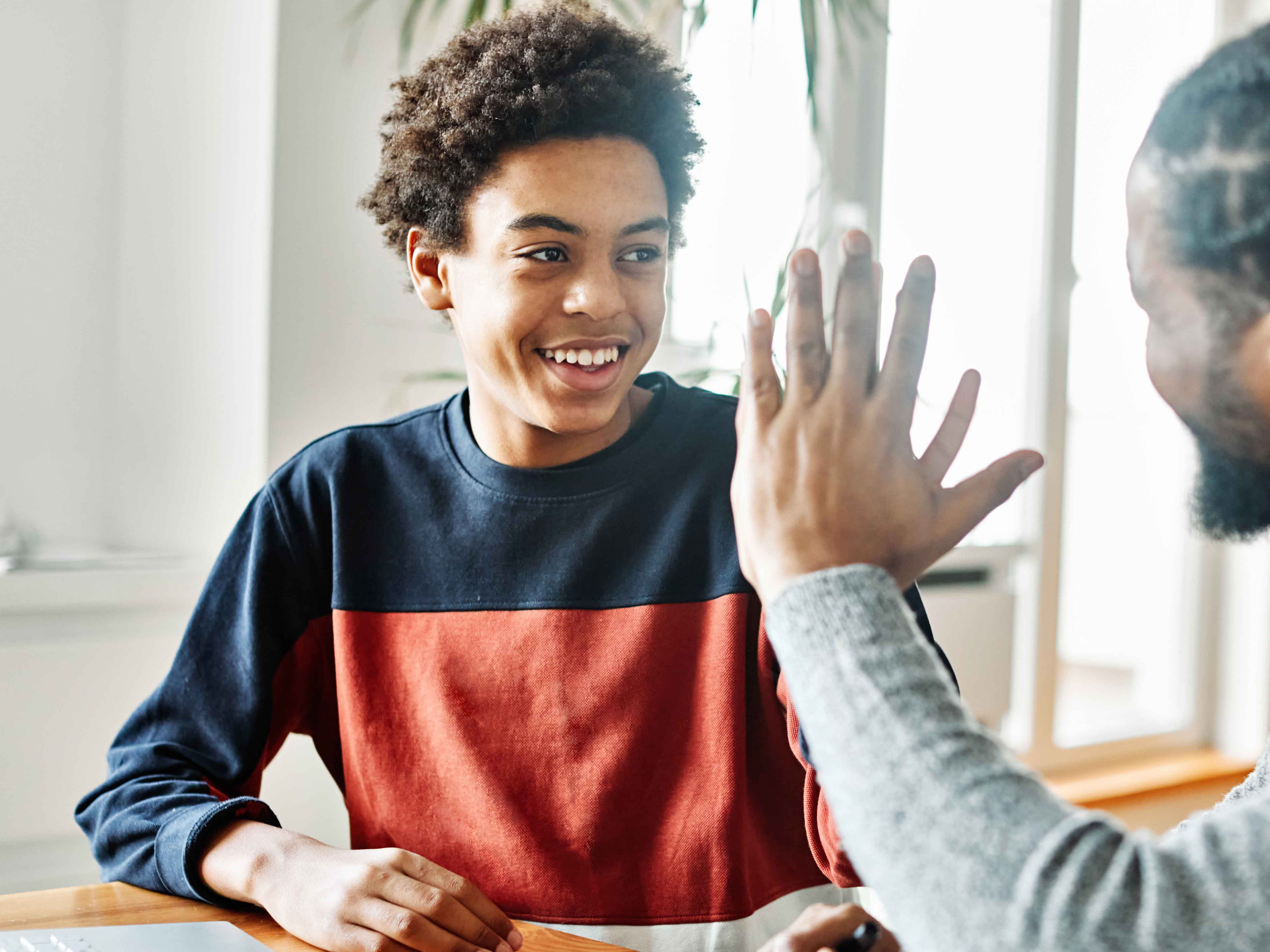 smiling teen looking intently at adult who is talking with him