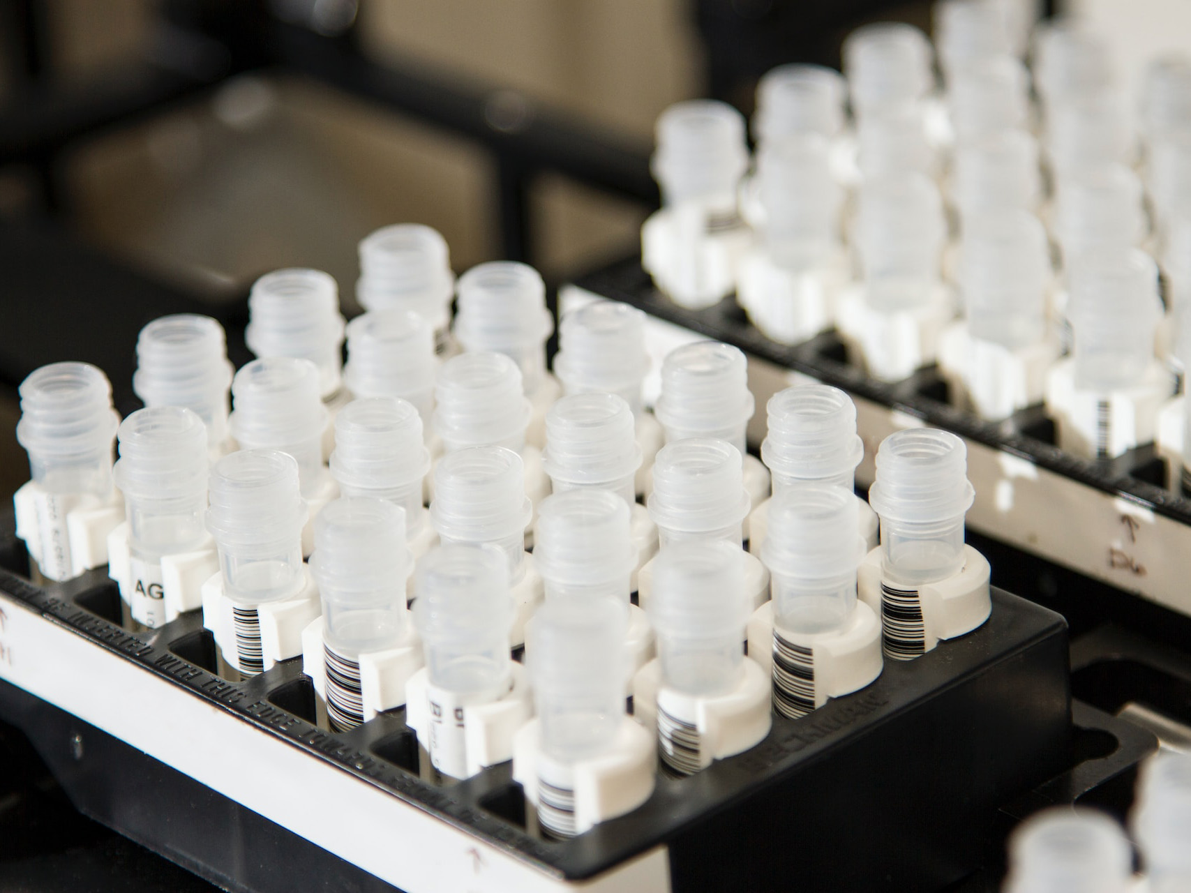 two racks of vials with white caps