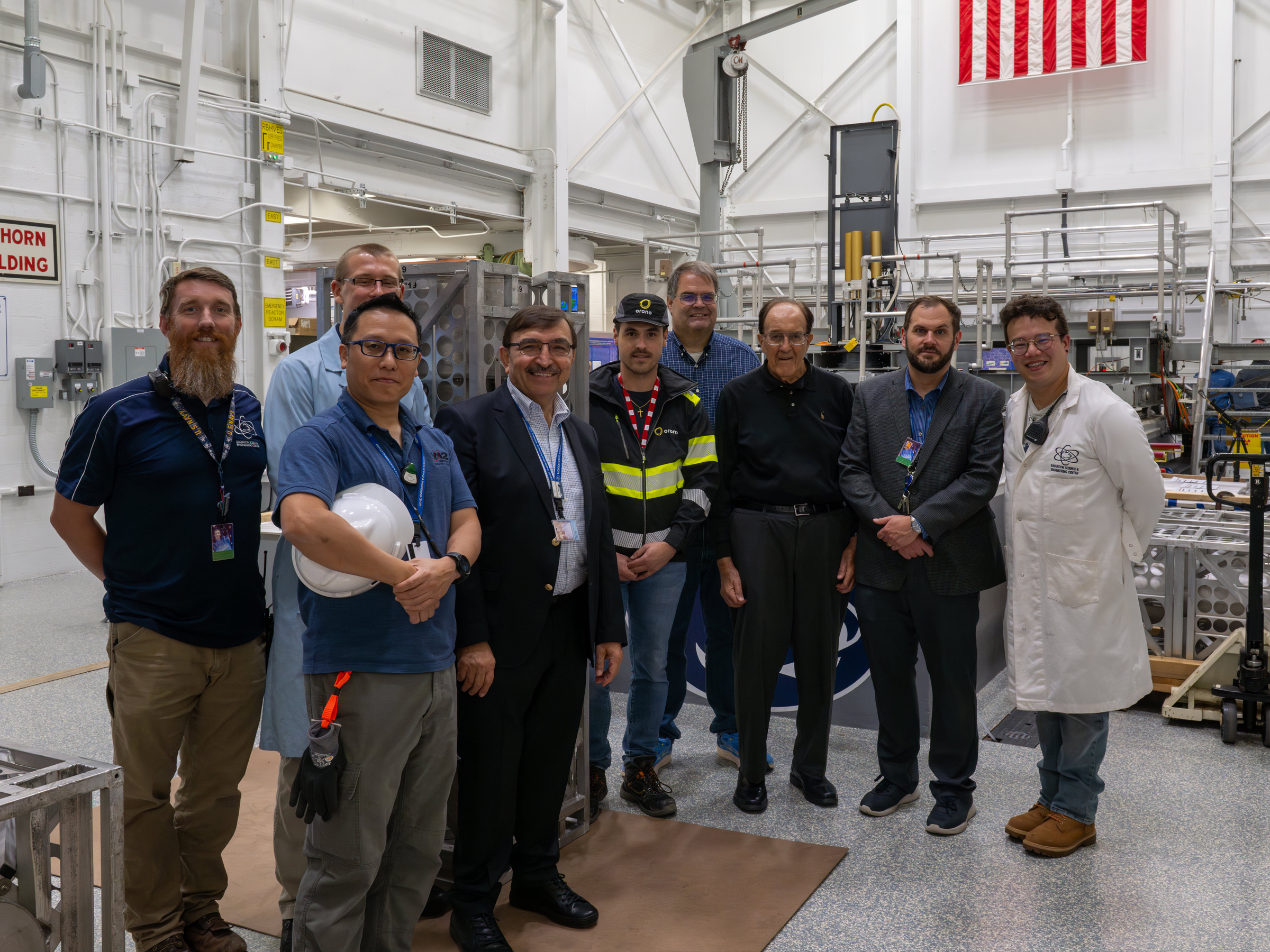 group of people pose for photo near nuclear reactor with new shipment of fuel