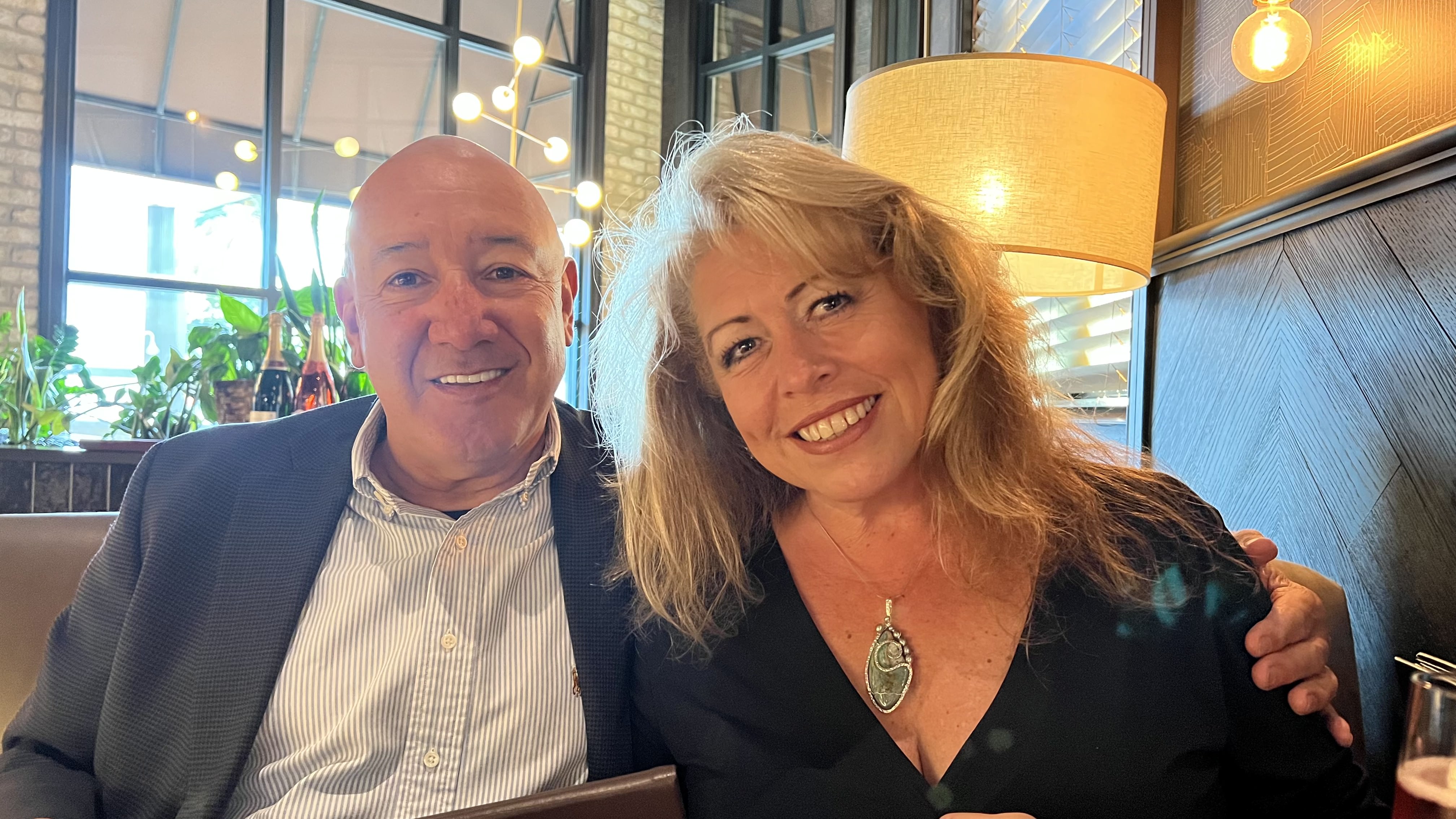 Fernando Montes and Carolyn Inhoffer Montes sitting at a restaurant and smiling at the camera