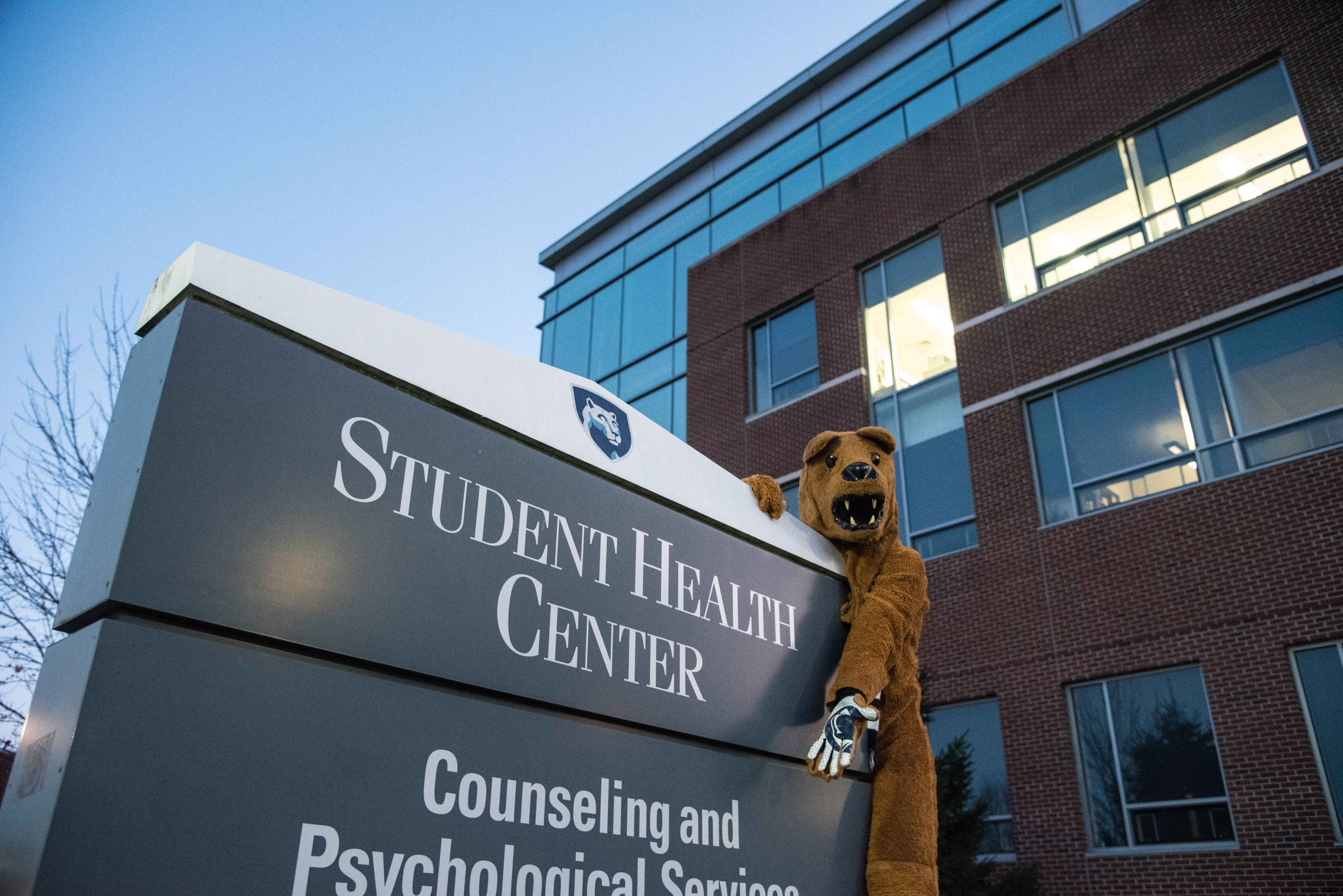 Nittany Lion posing in front of the Student Health Center sign