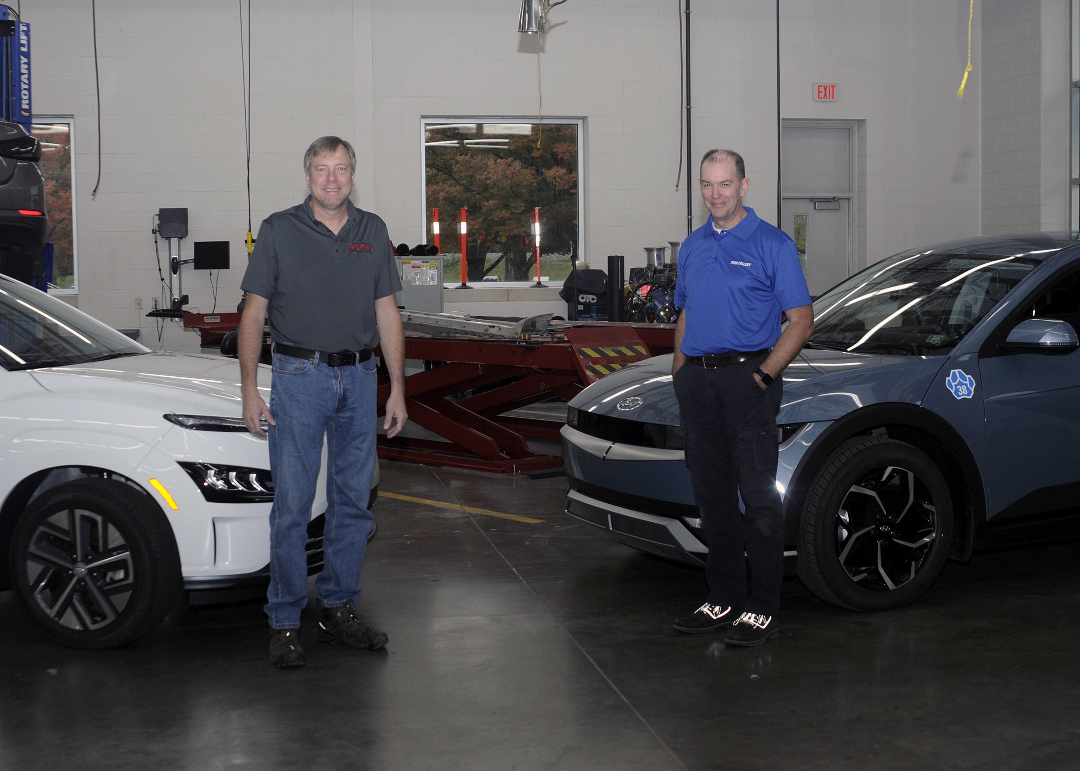 Two people stand with two electric vehicles